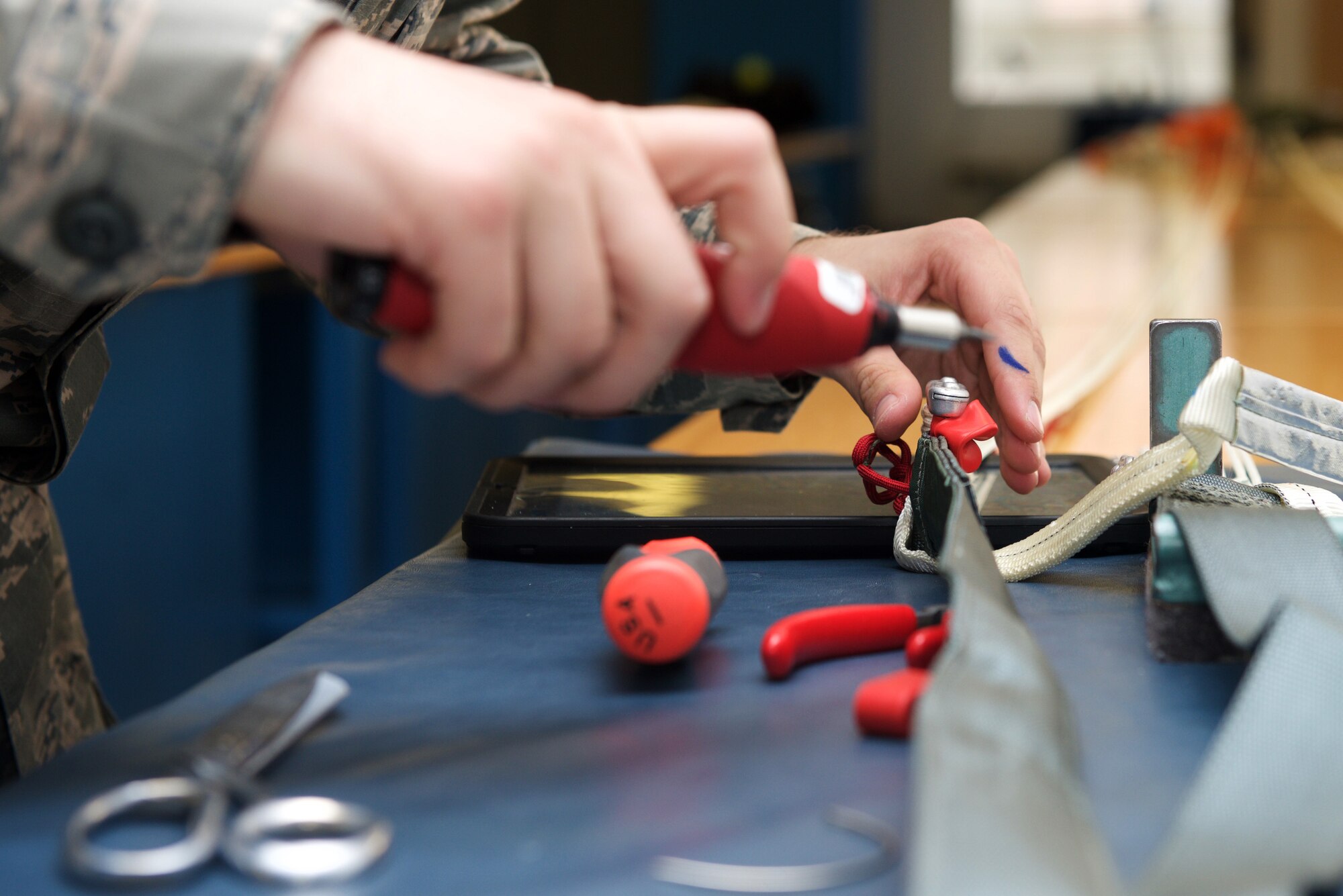 U.S. Air Force Airman 1st Class Justin Alfeld, 1st Operations Support Squadron aircrew flight equipment technician, ties the handles and straps of a parachute into place at Langley Air Force Base, Va., Jan. 29, 2016. Parachute technicians leave a half-inch of slack to help reduce opening force and the pressure put onto a pilot’s body upon ejection. (U.S. Air Force photo by Airman 1st Class Derek Seifert) 
