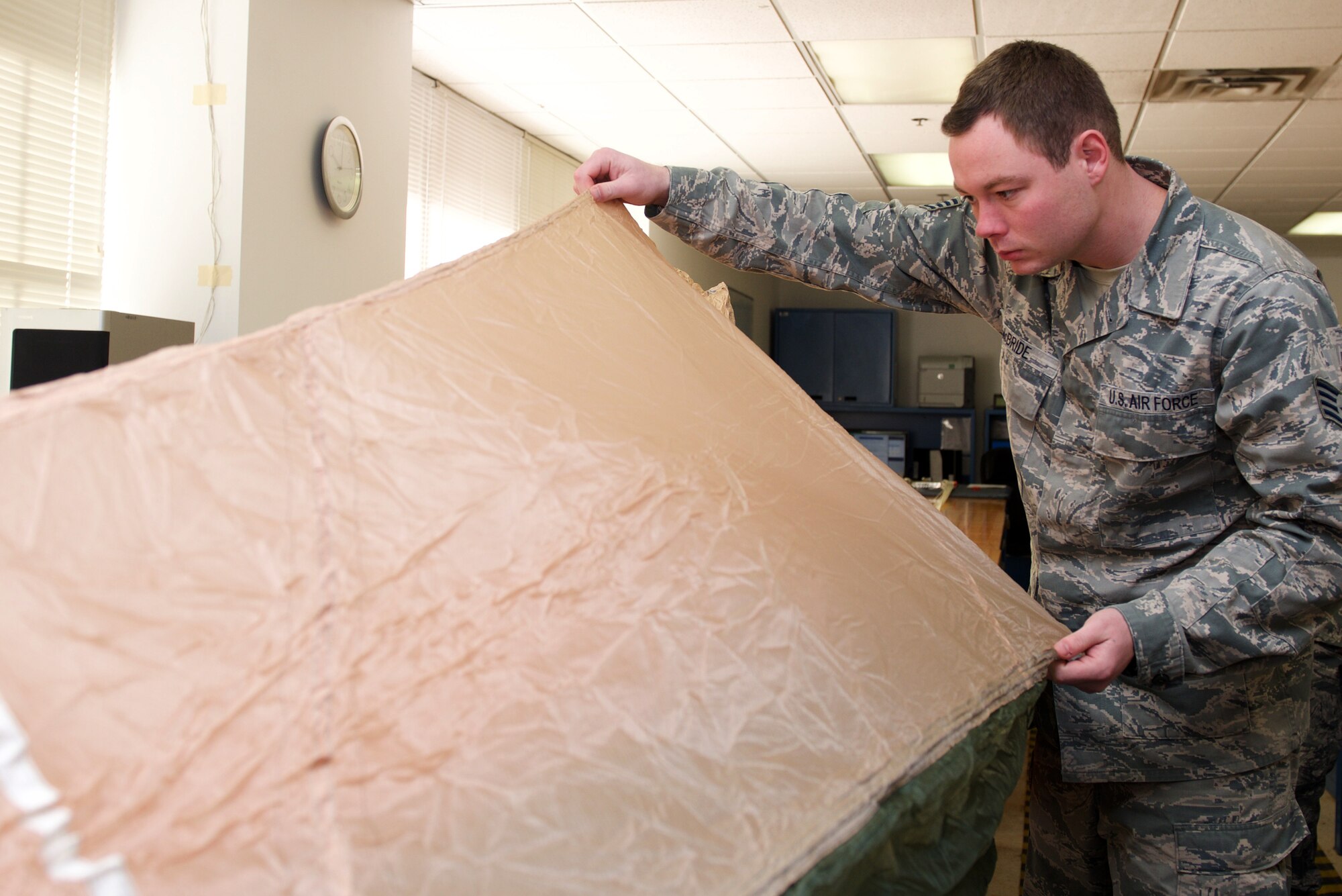 U.S. Air Force Staff Sgt. Kenneth McBride, Aircrew Flight Equipment noncommissioned officer in charge of the parachute section, looks for tears in a parachute gore at Langley Air Force Base, Va., Jan. 29, 2016. The Advanced Concept Ejection System II parachute has mechanisms built within to open on its own during ejection if a pilot becomes incapacitated. (U.S. Air Force photo by Airman 1st Class Derek Seifert)
