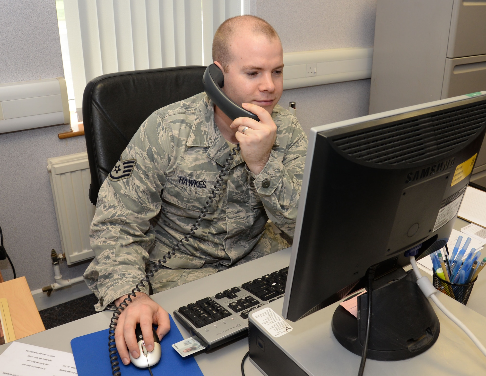 U.S. Air Force Staff Sgt. William Hawkes, 100th Air Refueling Wing NCO in charge of general and civil law, speaks to a customer on the telephone Feb. 8, 2016, on RAF Mildenhall, England. To ensure the tax center offers quality assistance, the Internal Revenue Service and the legal office will provide training to Team Mildenhall volunteers. (U.S. Air Force photo by Gina Randall/Released)