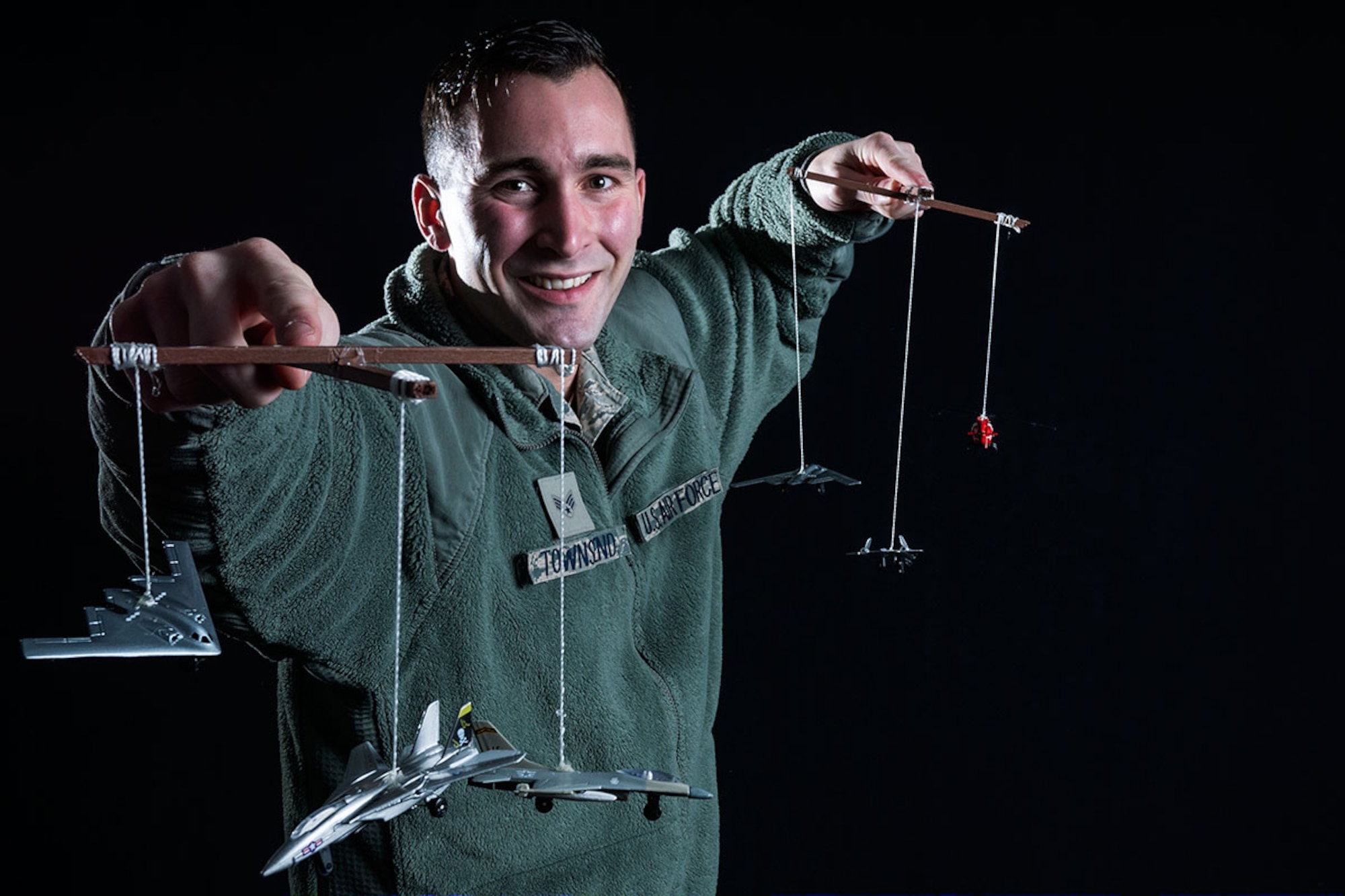 Senior Airman Matthew Townsend, an air traffic control journeyman assigned to the 3rd Operations Support Squadron holds up two marionettes depicting different aircraft he may need to guide safely to a runway. Air traffic control Airmen direct ground and airborne operations, reducing risks and maximizing efficiency. (U.S. Air Force photo by Airman 1st Class Kyle Johnson)