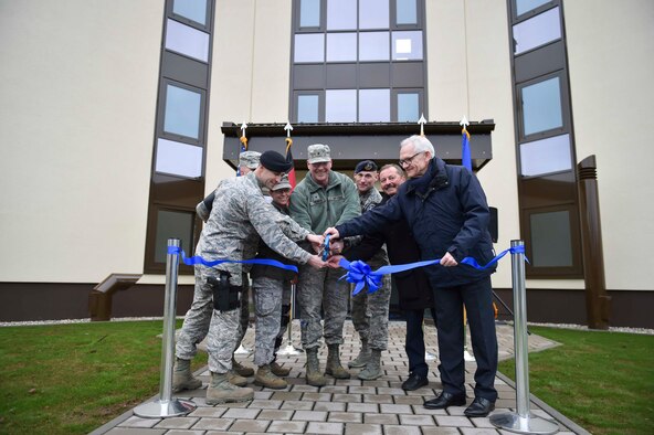 Brig. Gen. Jon T. Thomas, 86th Airlift Wing commander, and 569th United States Forces Police Squadron leaders, cut a ribbon for the grand opening of dorm 2818 at Kapaun Air Station, Germany, Feb. 5, 2016. The new dorm was constructed to be more energy efficient to help cut costs and maintain a healthier environment for Airmen that will live there. (U.S. Air Force photo/Staff Sgt. Sara Keller)