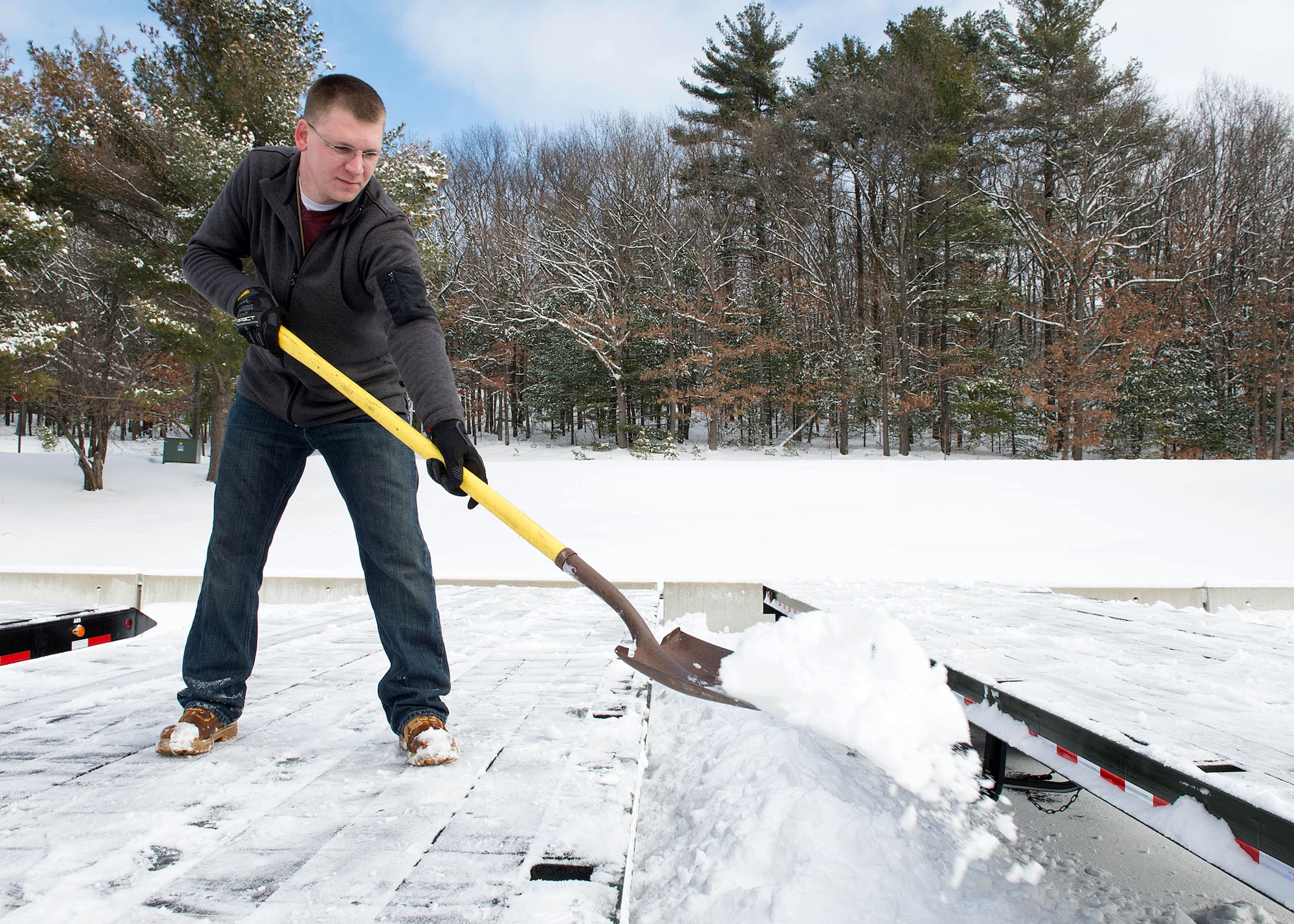 Francis Westleigh, 66th Logistic Readiness Squadron motor vehicle operator, removes snow from the bed of a tractor trailer in the motor pool parking lot Feb. 9. During winter snowstorms, some members of the 66 LRS team provide around-the-clock support to snow removal operations for the maintenance and repair of all snow removal vehicles, including immediate repair response for all breakdowns that occur during operations. (U.S. Air Force photo by Jerry Saslav)