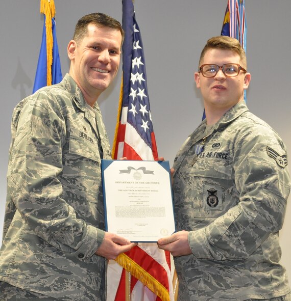 Col. John Devillier, 88th Air Base Wing commander, presents Senior Airman John Lucic with the citation following the pinning on of his AF Achievement Medal at a Wing staff meeting Jan 26. (U.S. Air Force photo/Gina Marie Giardina)