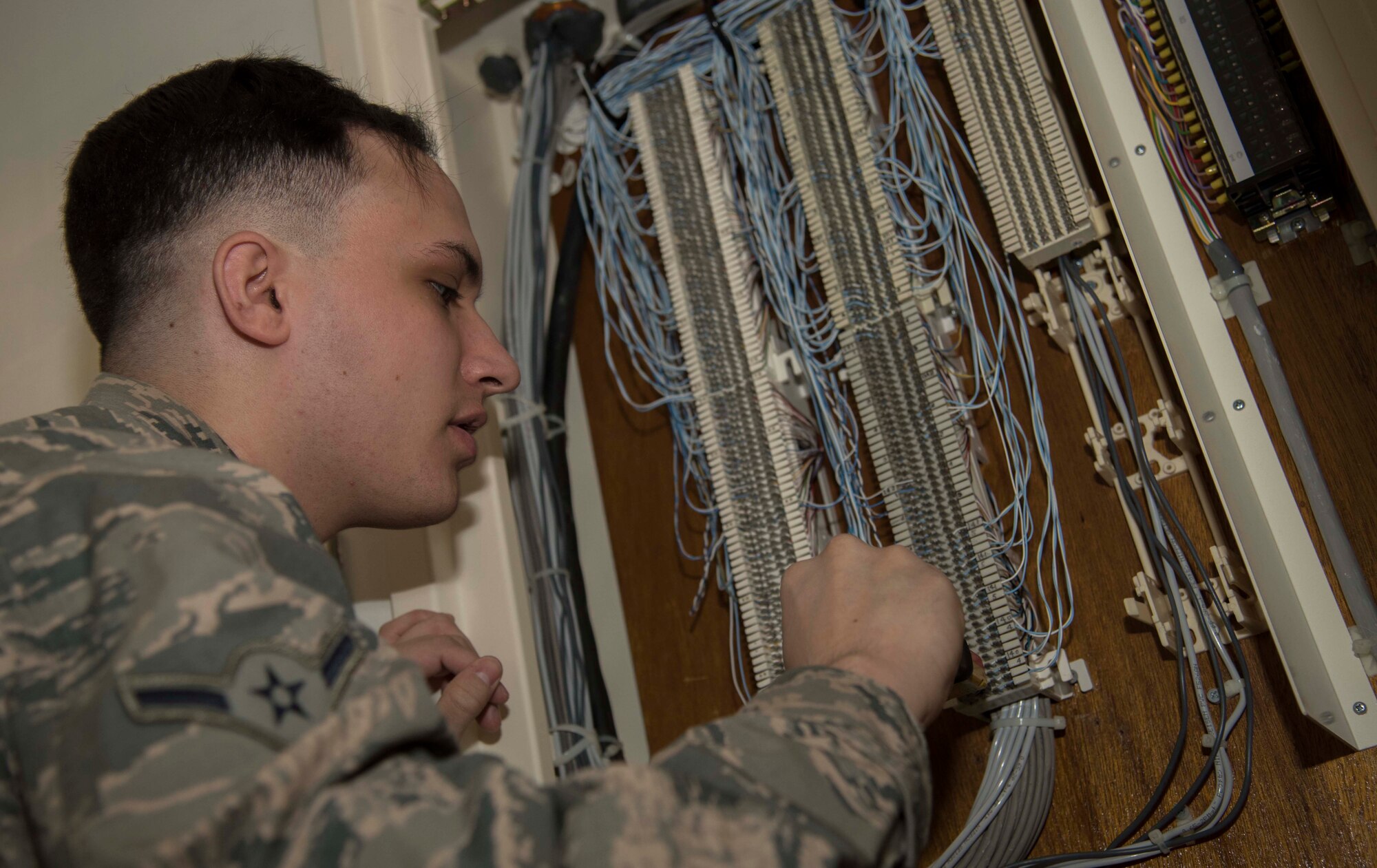 U.S. Air Force Airman Matthew Kennison, a client systems technician with the 35th Communications Squadron, adjusts cable heads at Misawa Air Base, Japan, Feb. 10, 2016. Although Misawa AB is transitioning to a Voice over Internet Protocol system for phones, the majority of the base talks through an analog phone system. Since this system doesn’t run through the internet, client system technicians perform installation and troubleshooting through punchboards located on the walls of buildings. (U.S. Air Force photo by Airman 1st Class Jordyn Fetter)