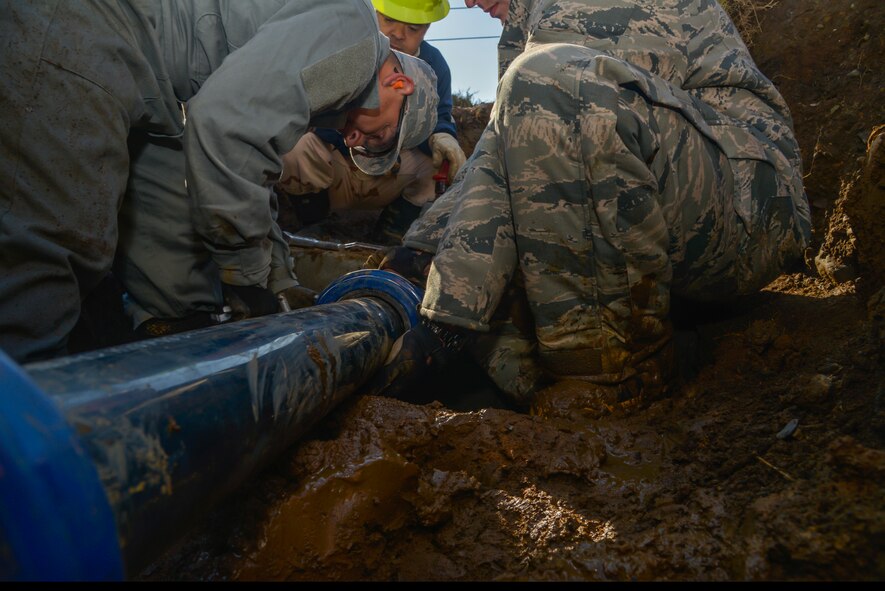 Staff Sgt. Leeroy Bocanegra, 374th Civil Engineer Squadron water fuel system maintenance craftsman, tightens a bolt on a Hymax mechanical coup link on a pipeline at Yokota Air Base, Japan, Feb. 9, 2016. After shutting off the water, the maintenance section used a K-12 cutting saw to cut off part of the metal pipeline and place a new pipe with two Hymax mechanical coup links. (U.S. Air Force photo by Senior Airman David Owsianka/Released)