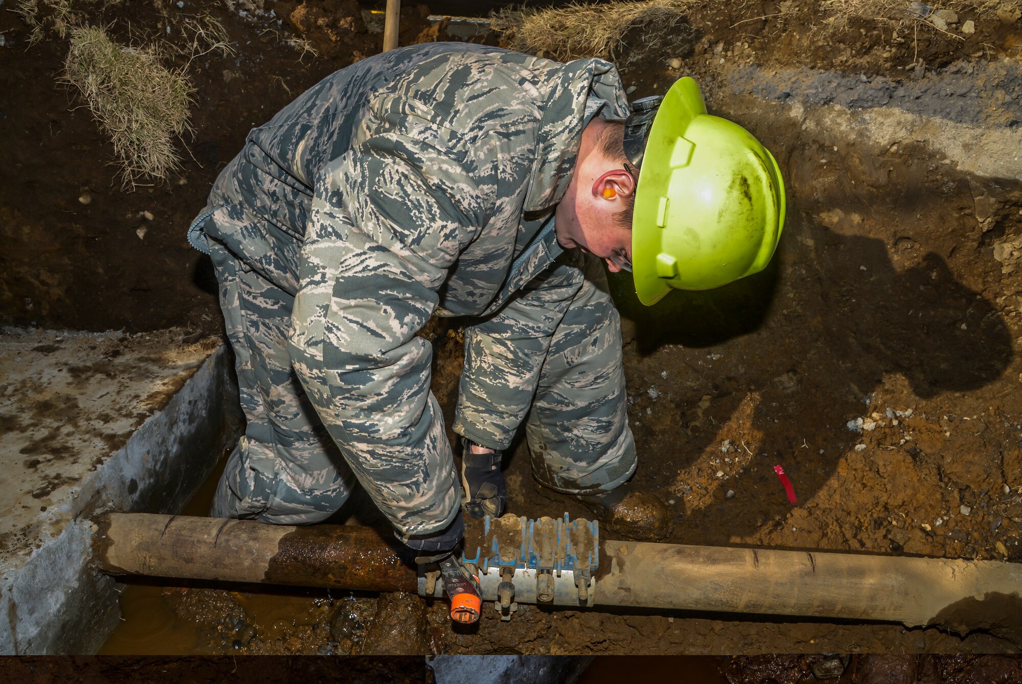 Airman 1st Class Colton Hunkeapillar, 374th Civil Engineer Squadron water fuel system maintenance journeyman, loosens bolts on a full circle clamp on a pipeline at Yokota Air Base, Japan, Feb. 9, 2016. After shutting off the water, the maintenance section used a K-12 cutting saw to cut off part of the metal pipeline and place a new pipe with two Hymax mechanical coup links. (U.S. Air Force photo by Senior Airman David Owsianka/Released)