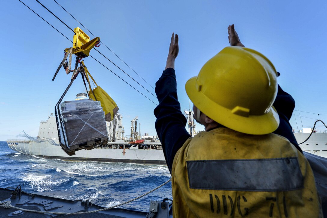 Navy Petty Officer 3rd Class John Stand signals aboard the USS Ross to a wench operator during an underway replenishment with the USNS Kanawha in the Mediterranean Sea, Feb. 7, 2016. Stand is a boatswain’s mate. The Ross is conducting a routine patrol to support U.S. security interests in Europe. Navy photo by Petty Officer 2nd Class Justin Stumberg