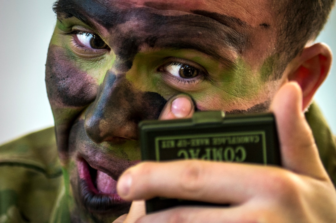 Army 1st Lt. Oliver Salman puts on camouflage paint before a night static-line jump during "large package week" training operations on Pope Army Airfield, N.C., Feb. 6, 2016. The training helps prepare airmen and soldiers for a subsequent joint access exercise. Air Force photo by Staff Sgt. Marianique Santos