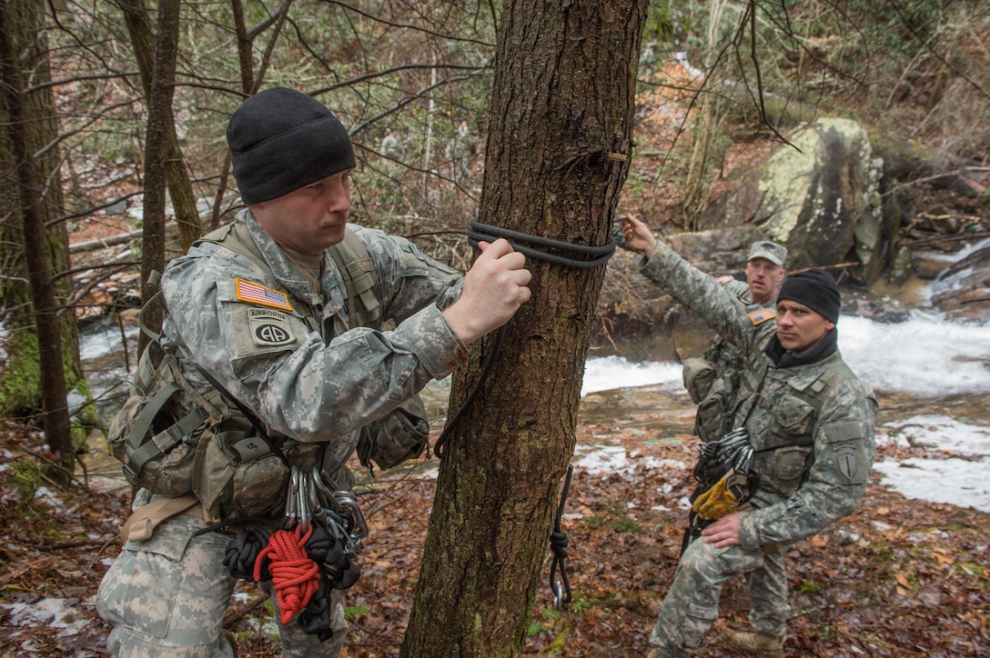 A U.S. Army Cpt. Andrew MacCornack (front) and Staff Sgt. Phillip Miller, both assigned to 5th Ranger Training Battalion, tie a rope to a tree while attempting to build a rope bridge over the Etowah River during the Basic Military Mountaineering Course at Camp Frank D. Merrill, Dahlonega, Ga., Jan. 21, 2016. The rope bridge is a "tight rope” or high load installation used to move personnel and equipment over terrain obstacles such as swift flowing mountain streams, ravines, and other deep gullies. (U.S. Army photo by Staff Sgt. Alex Manne/Released)