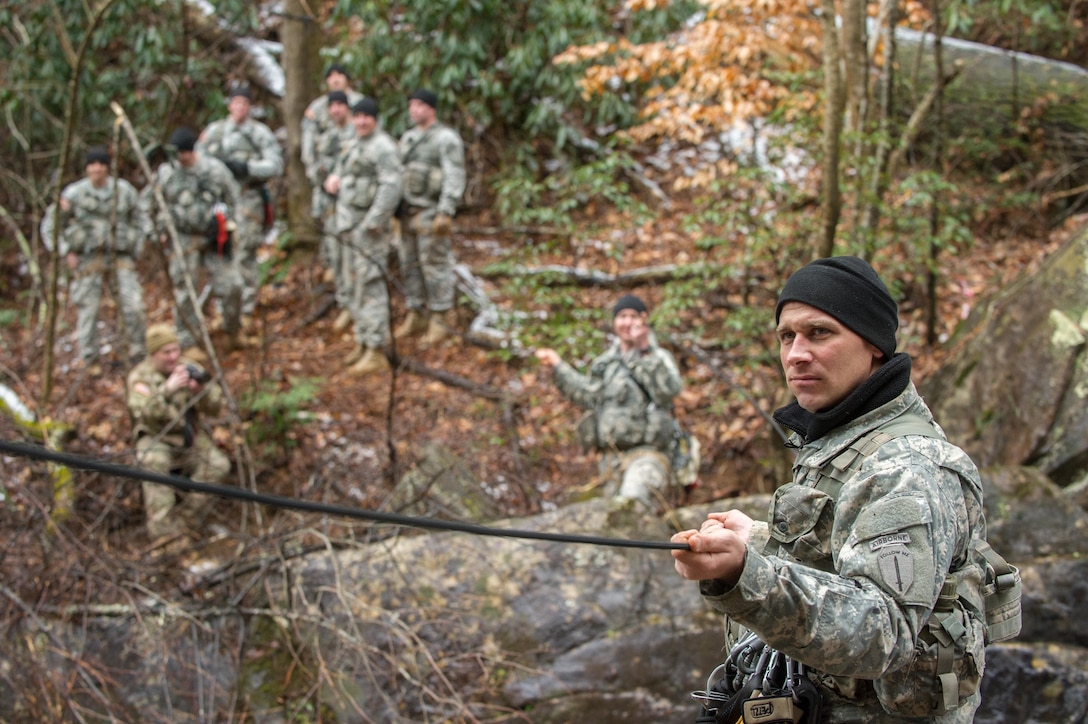 U.S. Army Staff Sgt. Phillip Miller, assigned to 5th Ranger Training Battalion, holds a rope while attempting to build a rope bridge during the Basic Military Mountaineering Course at Camp Frank D. Merrill, Dahlonega, Ga., Jan. 21, 2016. The rope bridge is a "tight rope” or high load installation used to move personnel and equipment over terrain obstacles such as swift flowing mountain streams, ravines, and other deep gullies. (U.S. Army photo by Staff Sgt. Alex Manne/Released)