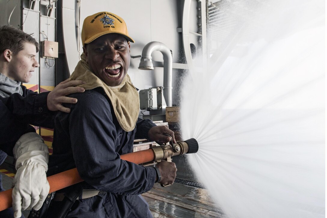 U.S. Navy Ensign Ty Downing demonstrates proper fire hose techniques during a general quarters drill in the hangar bay of the aircraft carrier USS Dwight D. Eisenhower, Feb. 9, 2016. Downing is the fire marshal on the Eisenhower, currently underway for the upcoming Board of Inspection and Survey. Navy photo by Petty Officer 3rd Class J. Alexander Delgado
