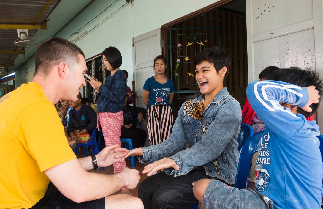 160207-N-RM689-536 SATTAHIP, Thailand (Feb. 7, 2016) - Lt. Shawn Callihan, assigned to amphibious dock landing ship USS Ashland (LSD 48), plays a hand game with children who attend Baan Kru Boonchoo for Special Children during a volunteering event. Ashland is assigned to the Bonhomme Richard Ready Group, and is participating in exercise Cobra Gold 16, a Thai- U.S. co-sponsored multinational joint exercise designed to advance regional security by exercising a robust multinational force from nations sharing common goals and security commitments in the Indo-Asia-Pacific region.