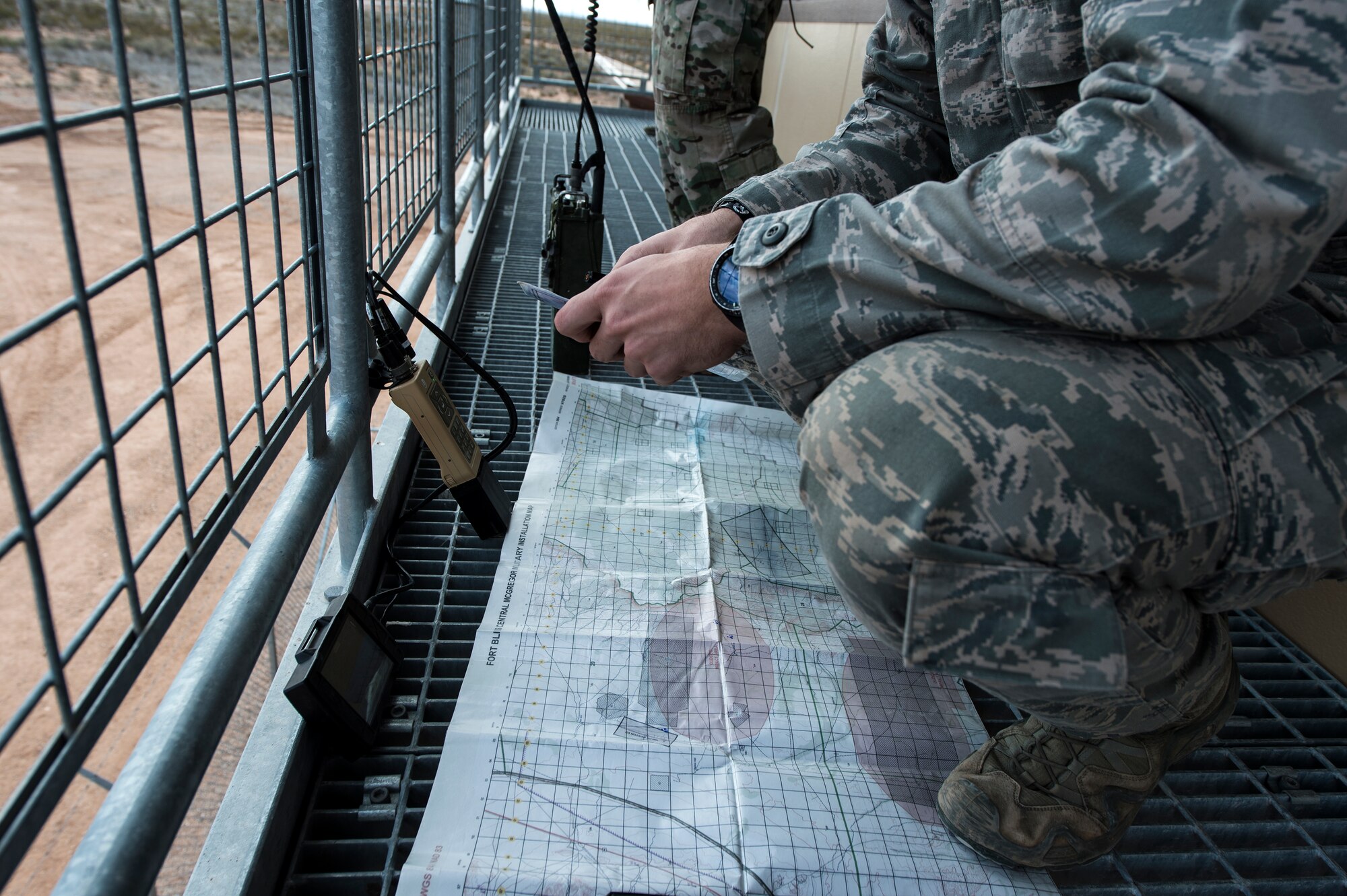 A map and an AN/PRC-117G Multi-band Manpack Radio rest on a balcony during the joint exercise, Iron Focus, Feb. 2, 2016, at Oro Grande Training Complex at Fort Bliss, Texas. The tactical satellite radio allows joint terminal attack controllers to communicate with pilots and notify them when they are cleared to drop bombs. (U.S. Air Force photo by Senior Airman Olivia Dominique/Released) 