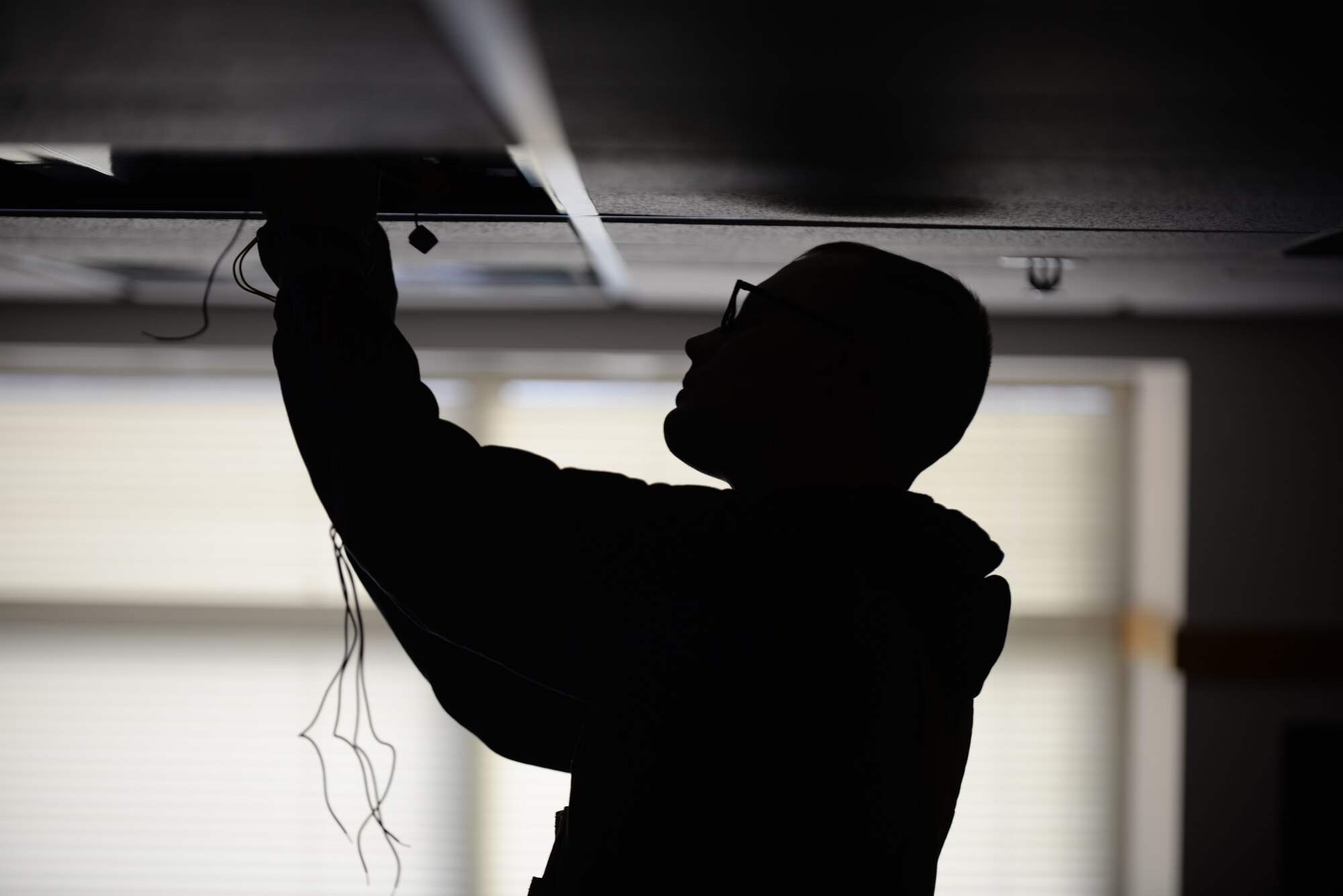 Senior Airman Daniel Hatfield, 28th Civil Engineer Squadron electrical systems technician, changes a phosphorous light fixture at Ellsworth Air Force Base, S.D., Jan. 26, 2016. Phosphorous bulbs are ignited by a ballast, which causes a small spark to light the phosphor in the bulbs to turn on the lights. (U.S. Air Force photo by Airman Sadie Colbert/Released)