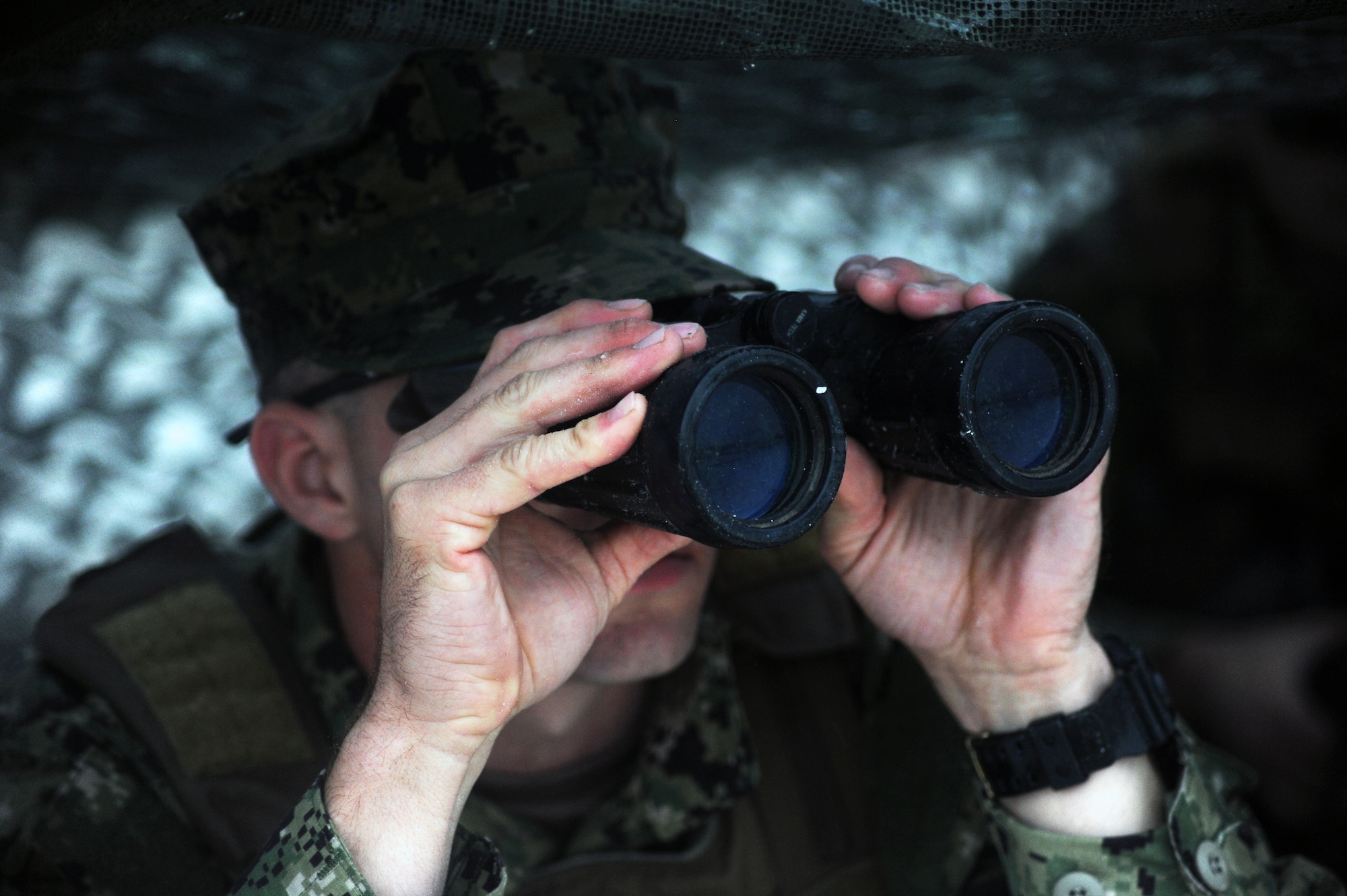A U.S. Coast Guard Port Security Unit 307 member uses binoculars to inspect the coast during a field training exercise at MacDill Air Force Base, Fla., Feb. 6, 2016. The member used tactical maneuvers to simulate keeping an opposing force from penetrating their security. (U.S. Air Force photo by Senior Airman Danielle Quilla)