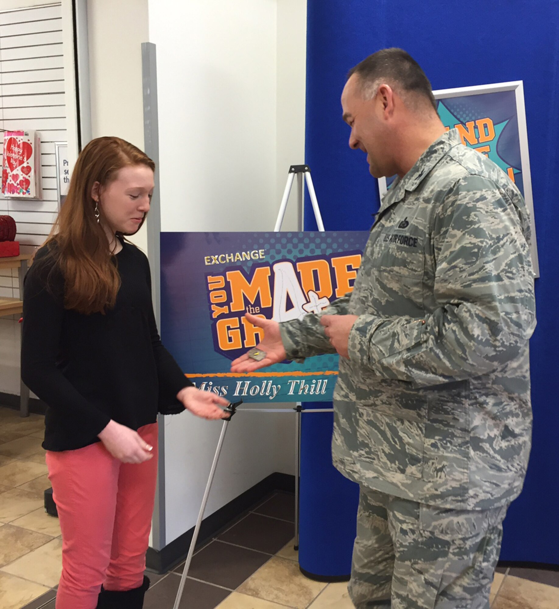 Holly Thill, winner of a $2,000 prize in the Army and Air Force Exchange Service’s worldwide “You Made the Grade” sweepstakes, receives a coin Feb. 5 from Col. David Kretz, 88th Mission Support Group commander, for her generosity in donating most of her $2,000 prize to purchase items for homeless people.  (Skywrighter photo/Amy Rollins)