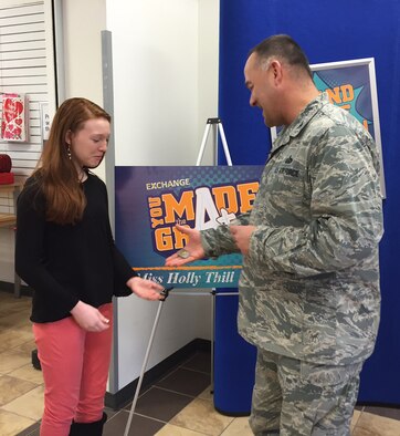 Holly Thill, winner of a $2,000 prize in the Army and Air Force Exchange Service’s worldwide “You Made the Grade” sweepstakes, receives a coin Feb. 5 from Col. David Kretz, 88th Mission Support Group commander, for her generosity in donating most of her $2,000 prize to purchase items for homeless people.  (Skywrighter photo/Amy Rollins)
