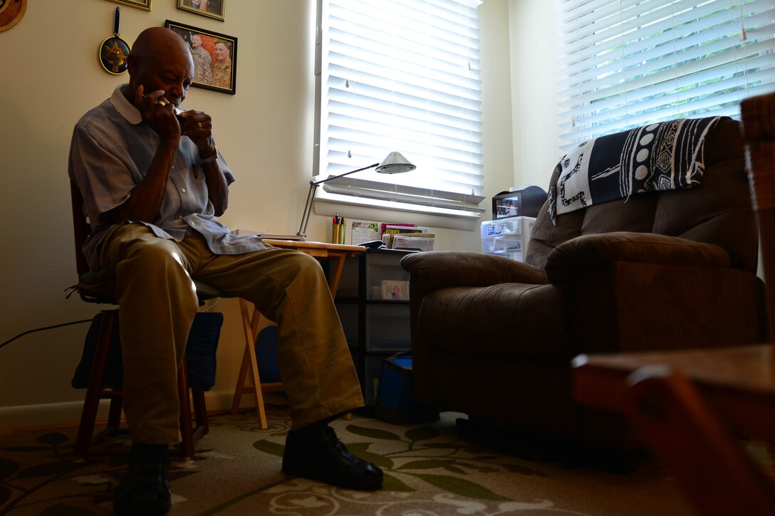 Retired U.S. Army Col. Aaron M. Dotson, a World War II and Vietnam War veteran, plays the harmonica in his room in Hampton, Va., Aug. 8, 2015. Before receiving a commission into the Army as a social work officer, Dotson studied music at Fisk University in Nashville, Tenn. (U.S. Air Force photo by Staff Sgt. Natasha Stannard)
