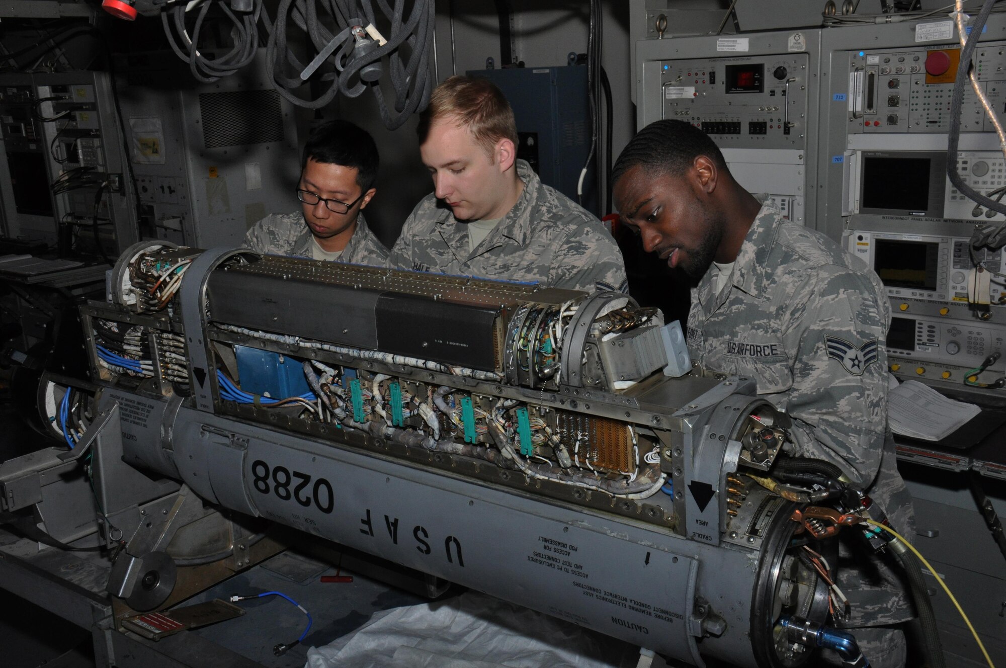 Airman 1st Class Long Nguyen, from Seattle, Washington, (left), Senior Airman Garette Hale from Littleton, New Hampshire (Center), and Senior Airman Romanov Saint-Fort (right), 379th Expeditionary Maintenance Squadron electronic countermeasures technicians, work on an electronic warfare attack pod at Al Udeid Air Base, Qatar Feb. 9. The Airmen are part of the electronic countermeasures section of the avionics flight and are responsible for maintaining $83 million in equipment. The avionics flight performed 56 maintenance inspections over the past six months. (U.S. Air Force photo by Tech. Sgt. James Hodgman/Released)