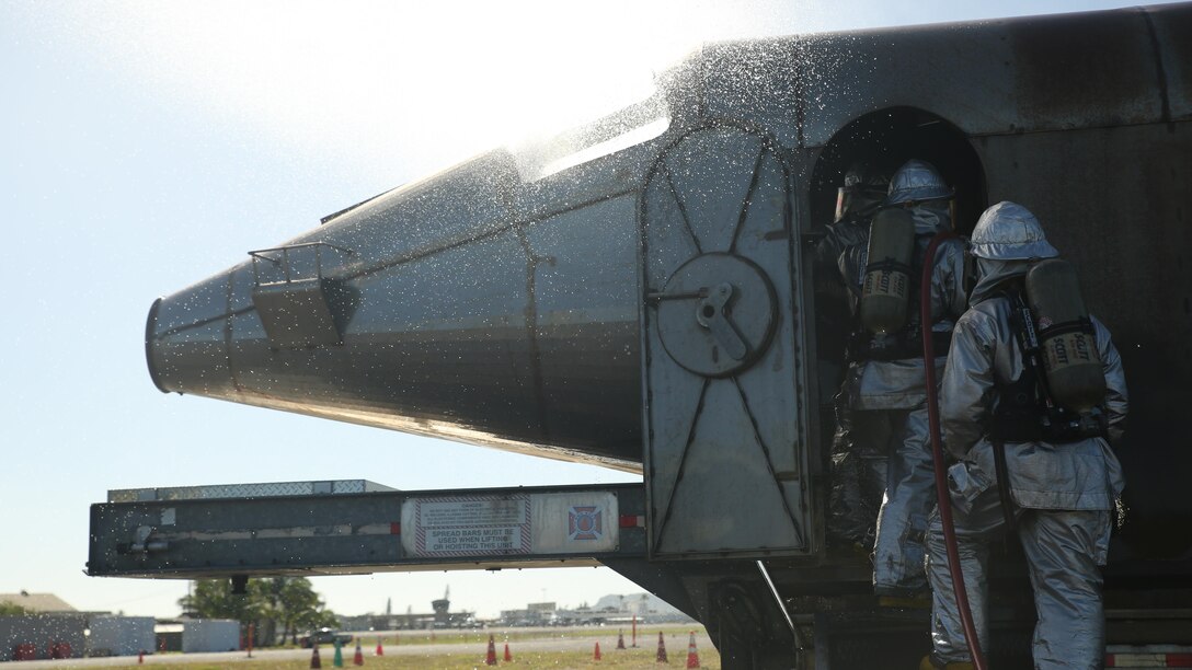 Marines with Aircraft Rescue Fire Fighting rush into a simulated burning aircraft during burn training aboard Marine Corps Air Station Kaneohe Bay on Feb. 10, 2016. The mission of ARFF is to protect property and save lives, which means the Marines need to be suited up and moving out within seconds of a call. ARFF rescue men work together to prevent aircraft fires, house fires and any other emergency on the airfield and on base.