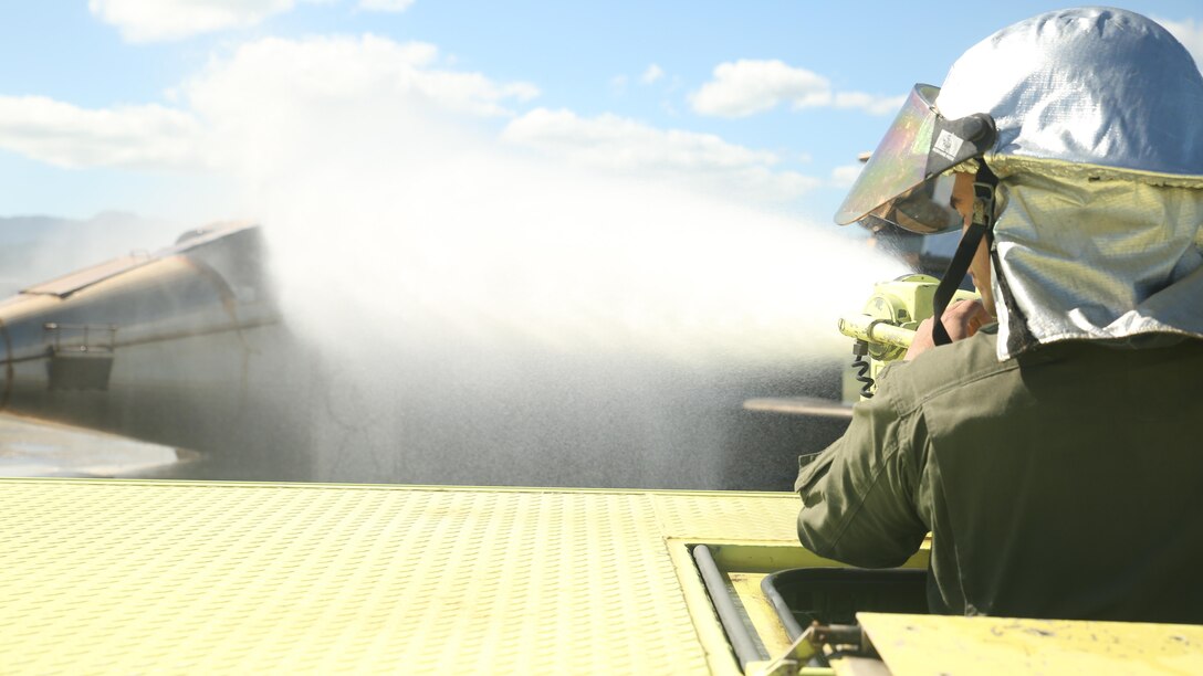 Pfc. Randy Gutierrez, an Air Rescue Fire Fighting turret operator with Kaneohe Bay Marine Corps Air Station, fires a water canon to cool down a simulated burning aircraft on Feb. 9, 2016. The mission of ARFF is to protect property and save lives, which means the Marines need to be suited up and moving out within seconds of a call. ARFF rescue men work together to prevent aircraft fires, house fires, and any other emergency on the airfield and on base.