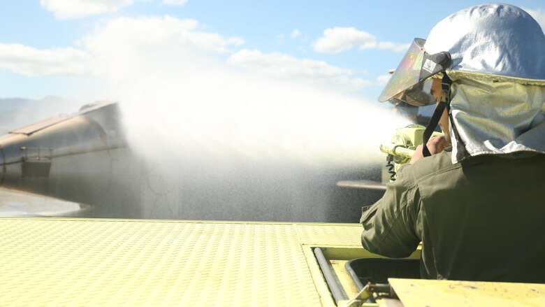 Pfc. Randy Gutierrez, an Air Rescue Fire Fighting turret operator with Kaneohe Bay Marine Corps Air Station, fires a water canon to cool down a simulated burning aircraft on Feb. 9, 2016. The mission of ARFF is to protect property and save lives, which means the Marines need to be suited up and moving out within seconds of a call. ARFF rescue men work together to prevent aircraft fires, house fires, and any other emergency on the airfield and on base.