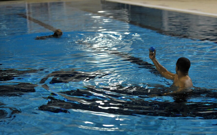 Staff Sgt. Anthony, a 380th Expeditionary Security Forces Squadron military working dog handler, holds up a rubber ball up for his K9 partner, Dini, age 11, during annual water-based aggression training at the base pool at undisclosed location in Southwest Asia, Jan. 18, 2016. The training was conducted to encourage the dogs to overcome their reluctance to entering the water and correctly performing their duties. (U.S. Air Force photo by Staff Sgt. Kentavist P. Brackin/released)