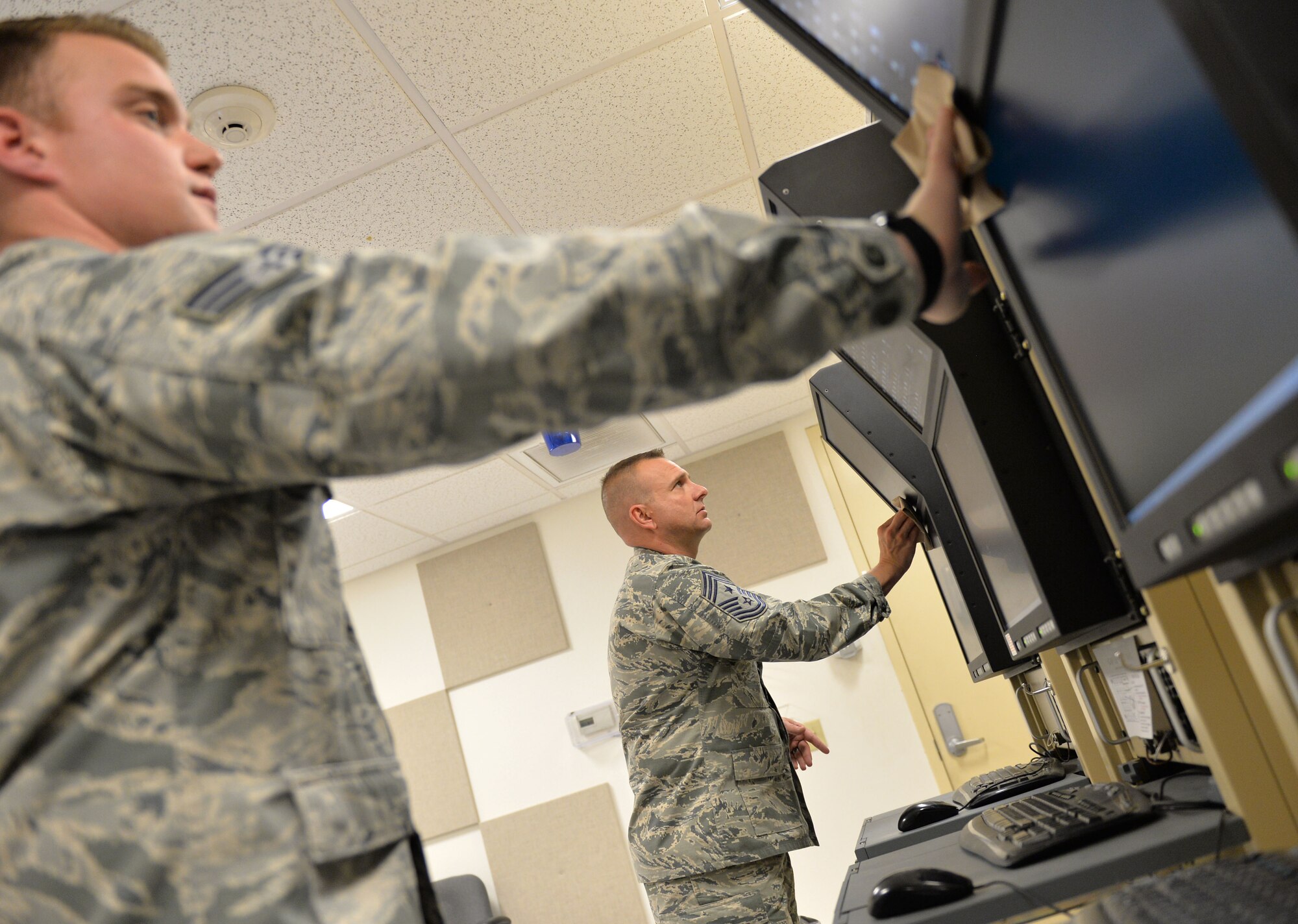 Chief Master Sgt. Michael Ditore, the 432nd Wing/432nd Air Expeditionary Wing command chief, right, cleans monitors with Senior Airman Robert, a 432nd Aircraft Communications Maintenance Squadron ground control station communications mechanic, Feb. 11, 2016, at Creech Air Force Base, Nev. They were wiping the screens as part of a preventative maintenance inspection. (U.S. Air Force photo/Senior Airman Christian Clausen)
