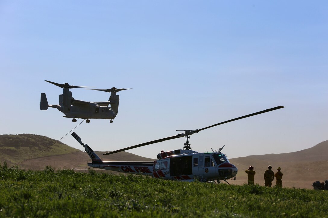 An MV-22B Osprey with Marine Medium Tiltrotor Squadron (VMM) 165 takes off to load the bucket while performing firefighting training while the California Department of Forestry and Fire Protection firefighters watch from below aboard Hemet-Ryan Air Attack Base, Calif., Feb. 11. The Marines with VMM-165 flew out to Diamond Valley Lake on Hemet-Ryan Air Attack Base to perform bucket dips in an effort to prove the aircraft was capable of such training while supporting Cal Fire.