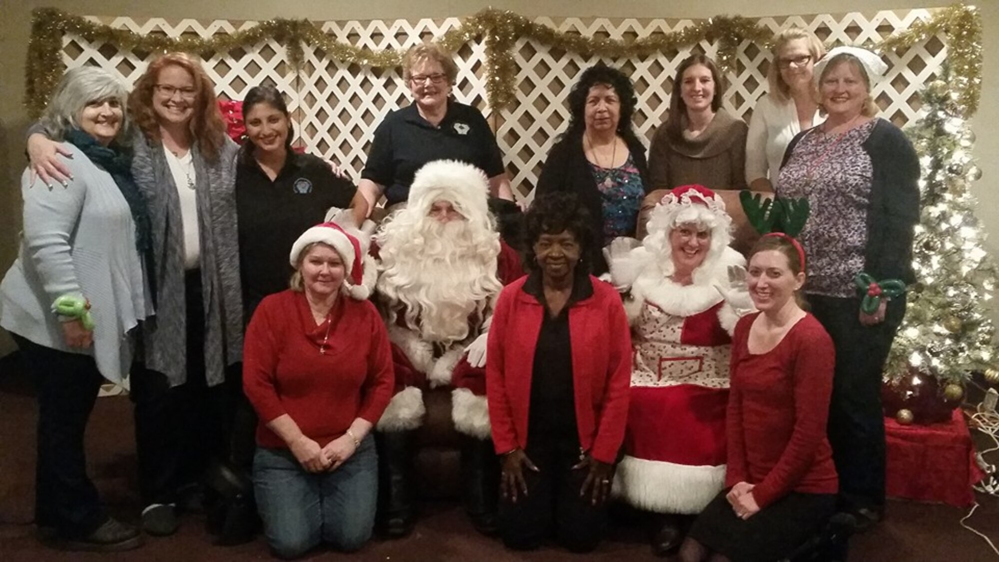 Members of the Enlisted Spouses Club Winter Wonderland Committee stand around Santa Clause at the 21st Annual Winter Wonderland at the Bellevue Social Center, Bellevue, Neb., Dec. 12, 2015. The event provides gifts and activities for the children of active duty or retired service members. (Courtesy photo)