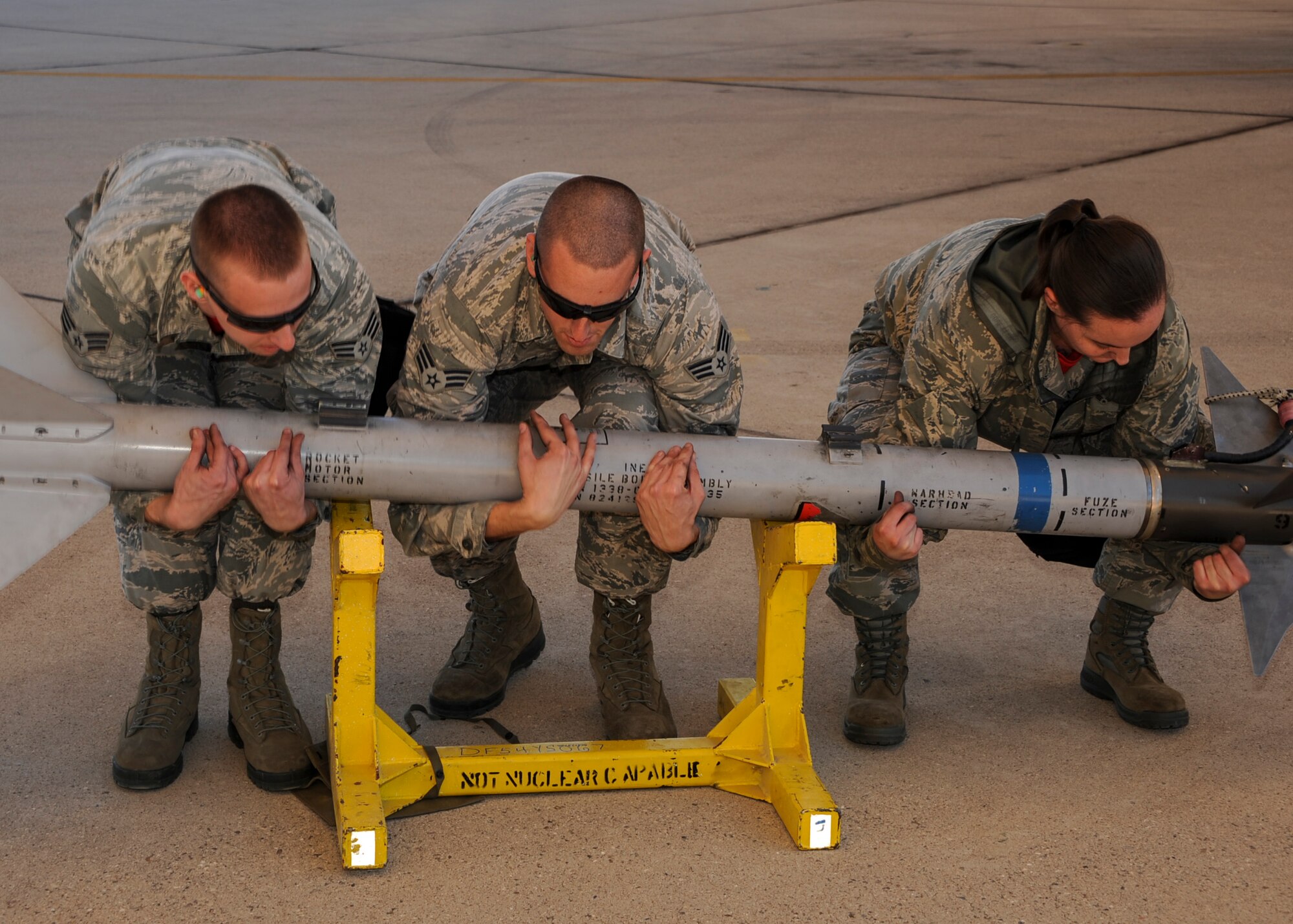 U.S. Air Force Senior Airmen Riley McIrvin, Joseph Fowler and Jordann Humphrey, 924th Maintenance Squadron weapons load crew members, lift an AIM-9 Sidewinder missile to load onto an A-10C Thunderbolt II during a load crew of the year competition at Davis-Monthan Air Force Base, Ariz., Feb. 5, 2016. Each of the four load crews competing in the contest consisted of three Airmen who won load crew of the quarter competitions the previous year. (U.S. Air Force photo by Airman Basic Nathan H. Barbour/Released)