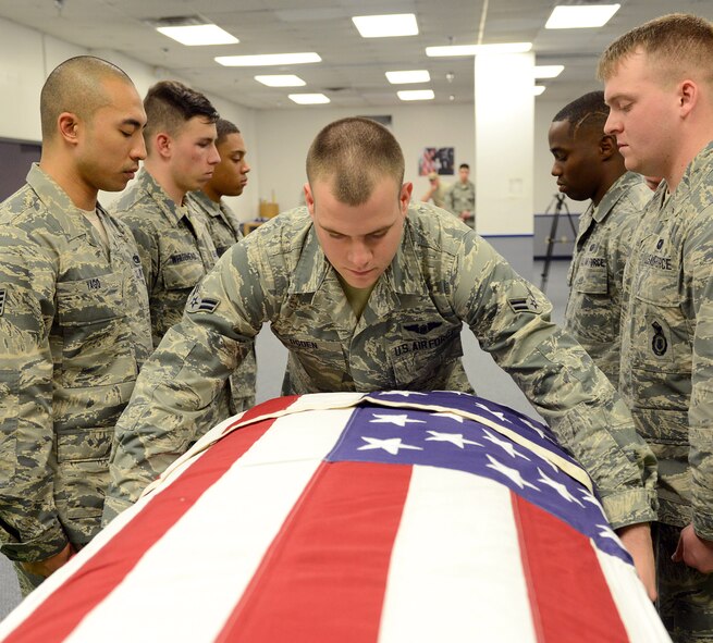 Airman 1st Class Mathew Ogden, Robins Honor Guard, drapes a U.S. flag over a casket during a funeral honors ceremony practice. Honor guard members serve for 180 days and practice about five hours each day to perfect the moves they will make during  military honors ceremonies. (U.S. Air Force photo by Tommie Horton)