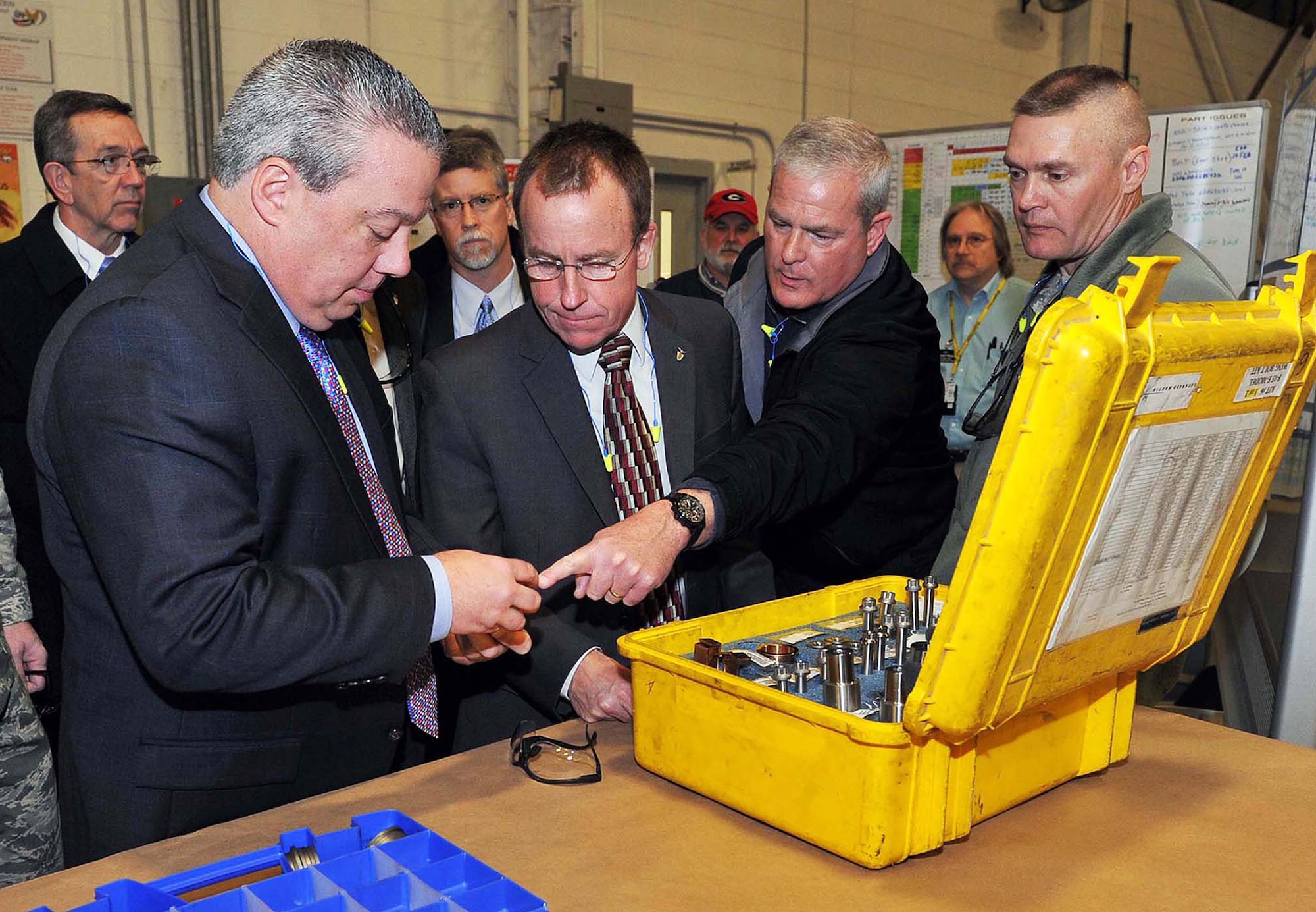 Thomas Fischer, Air Force Sustainment Center Robins Operating Location Engineering and Technical Management director; Jeffrey Allen, Air Force Sustainment Center executive director; Mike Arnold, 561st Aircraft Maintenance Squadron director; and Brig. Gen. Walter Lindsley, Warner Robins Air Logistics Complex commander; look at an F-15 pin. A recent change to how the part is used is an example of progress made during the F-15 transition plan. Allen was at Robins to receive Team Robins mission updates. (U.S. Air Force photo by Tommie Horton)