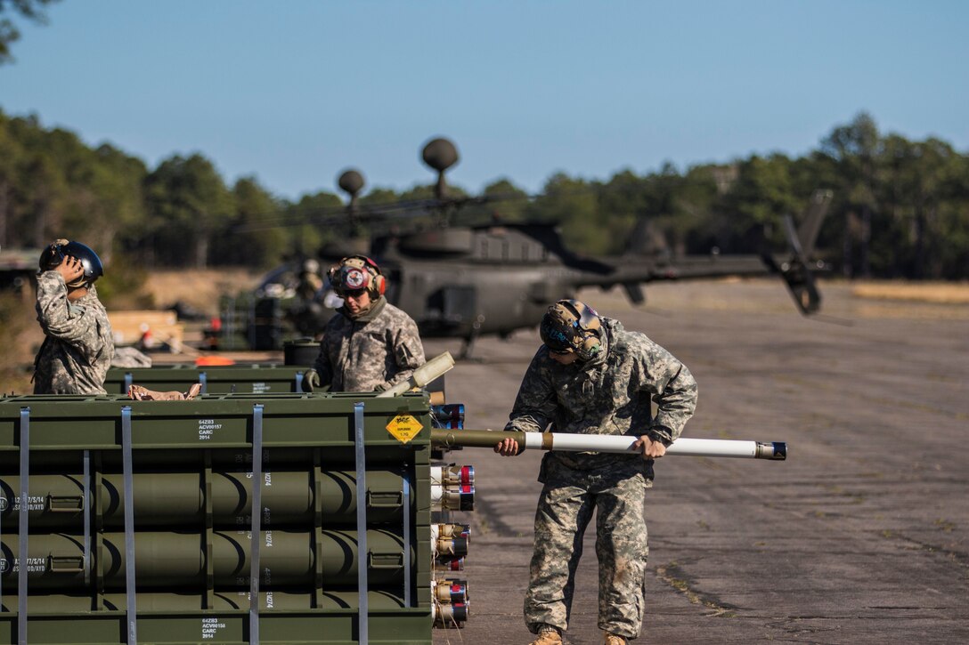 A soldier places felchette rockets in the ready tube of an OH-58 Kiowa Warrior helicopter on Marine Corps Outlying Field Atlantic, N.C., Feb. 8, 2016. The soldier is assigned to the 82nd Airborne Division’s 17th Cavalry Regiment, 82nd Combat Aviation Brigade. The rockets have to be unpackaged and inspected before being loaded onto the Kiowa, ensuring the pilots receive the best quality ammunition for the aerial gunnery range. Army photo by Staff Sgt. Christopher Freeman