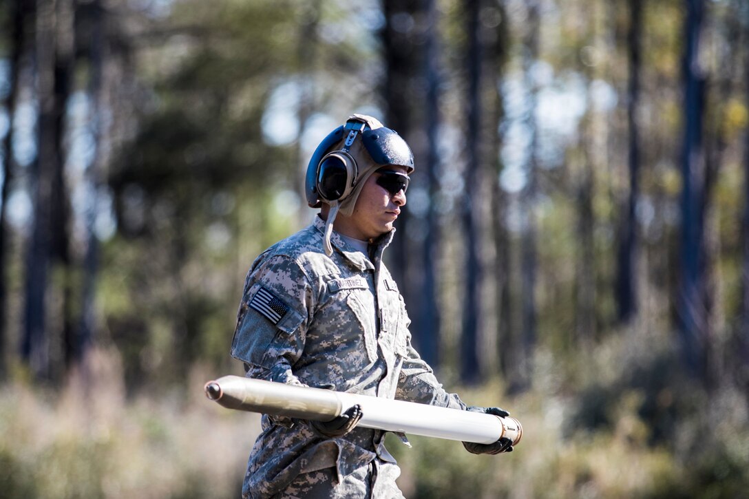 Army Pfc. Alejandro Martinez carries a felchette rocket to be loaded onto an OH-58 Kiowa Warrior helicopter on Marine Corps Outlying Field Atlantic, N.C., Feb. 8, 2016. Martinez is a petroleum supply specialist assigned to the 82nd Airborne Division’s 17th Cavalry Regiment, 82nd Combat Aviation Brigade. Army photo by Staff Sgt. Christopher Freeman