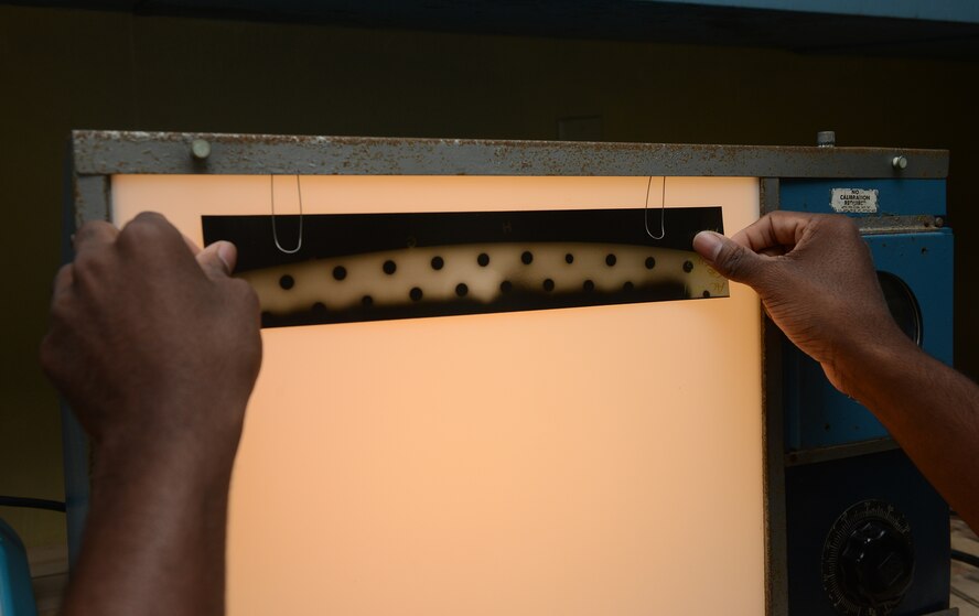 Senior Airman Clarence Tobias, 36th Maintenance Squadron non-destructive inspection specialist, checks an x-ray film of B-52 flaptracks for cracks Feb. 3, 2016, at Andersen Air Force Base, Guam. NDI is responsible for performing inspections of aircraft structural components to identify damages at a microscopic level. (U.S. Air Force photo/Airman 1st Class Arielle Vasquez)