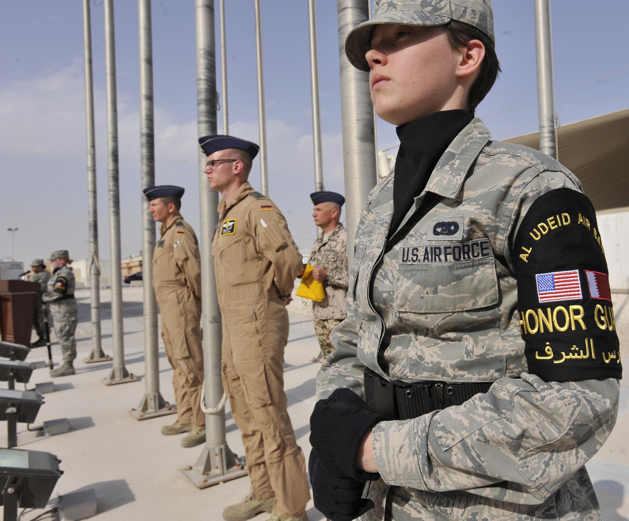 Senior Airman Nikole Warn, Al Udeid Air Base Honor Guard member, stands in position with German Air Force members during a flag raising ceremony at Al Udeid Air Base, Qatar, Feb. 8, 2016. The ceremony recognized the addition of Germany to the coalition supporting Operation Inherent Resolve. (U.S. Air Force photo by Master Sgt. Joshua Strang)