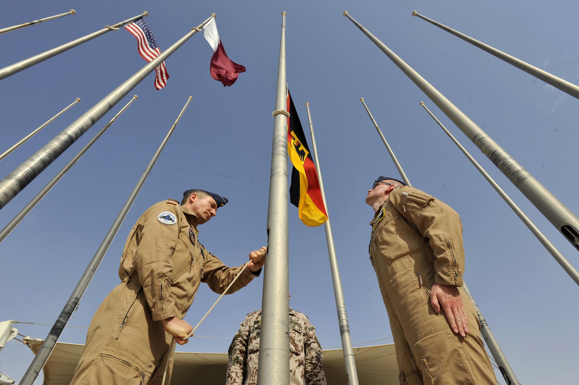 German Air Force members raise the German flag during a ceremony at Al Udeid Air Base, Qatar, Feb. 8, 2016. The ceremony recognized the addition Germany to the coalition supporting Operation Inherent Resolve. (U.S. Air Force photo by Master Sgt. Joshua Strang)
