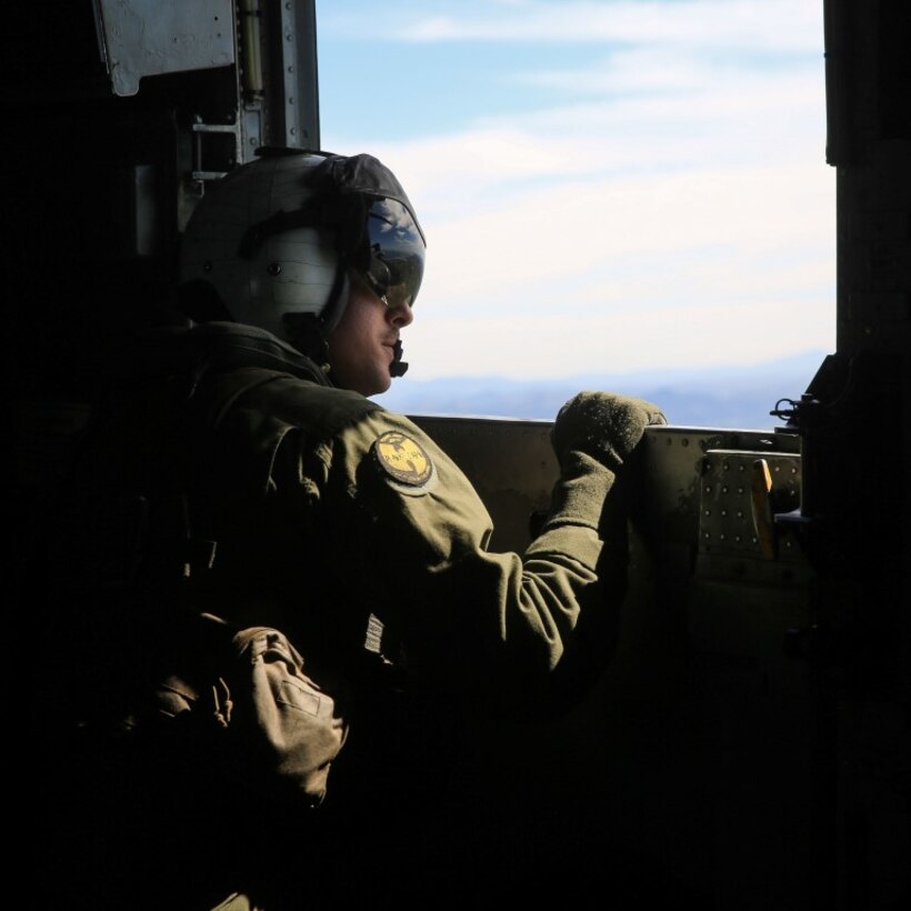 A Marine observes the objecive area below during a tactical recovery of aircraft and personnel, or TRAP, training scenario at Camp Pendleton, Calif., Feb. 10, 2015. Marine Heavy Helicopter Squadron 462, Marine Aircraft Group 16, 3rd Marine Aircraft Wing, provided aerial support for Weapons Company, 2nd Battalion, 4th Marine Regiment, 1st Marine Division during the daytime TRAP exercise. The Marine is with HMH- 462. (U.S. Marine Corps photo by Lance Cpl. Devan K. Gowans/Released)