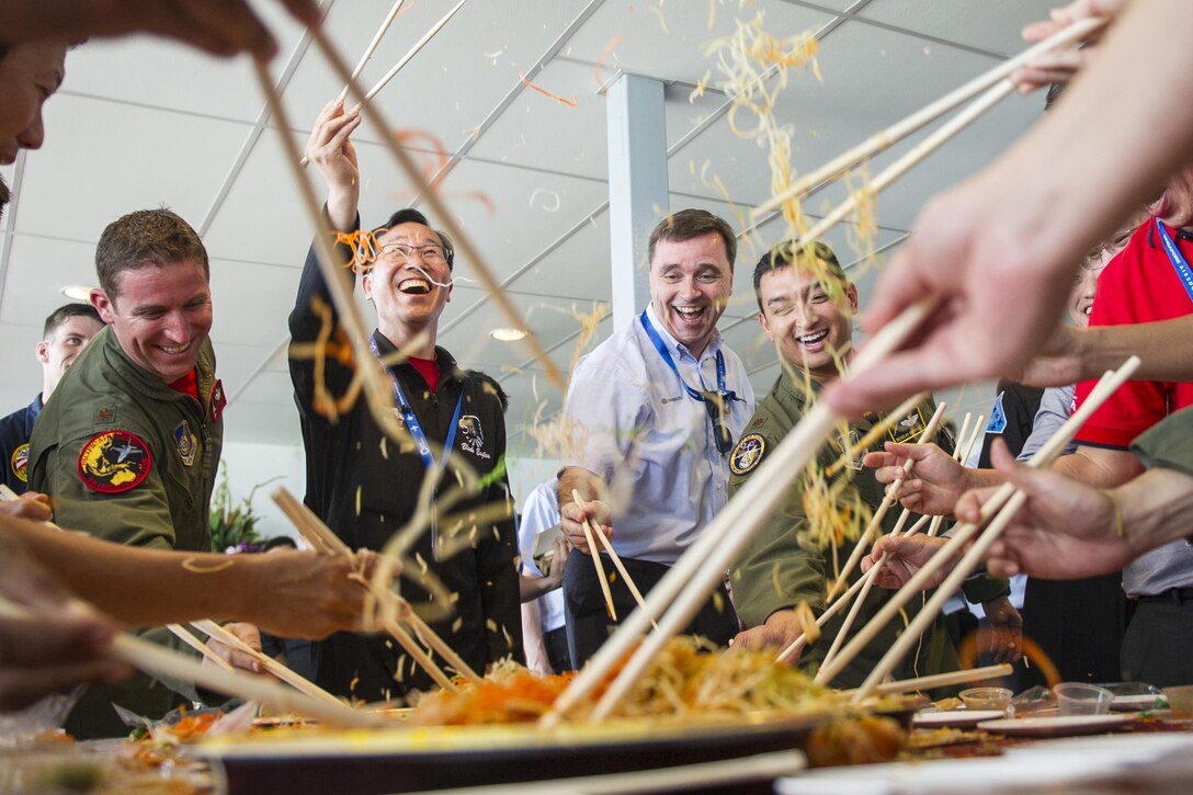 Aerial demonstration team members from the U.S., Singapore, South Korea, Malaysia and France use chopsticks to toss food during a lo hei dinner, a Lunar New Year tradition meant to bring good fortune, at Changi Airport, Singapore, Feb. 14, 2016. The team members participated in the custom before the start of the 2016 Singapore Airshow. Air Force photo by Capt. Raymond Geoffroy