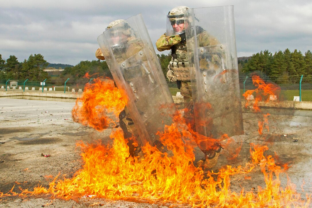 U.S. soldiers shield themselves from a bottle-based improvised flammable weapon, also known as a Molotov cocktail, during fire phobia training at the Joint Multinational Readiness Center in Hohenfels, Germany, Feb. 16, 2016. The soldiers are training alongside multinational counterparts for Kosovo Force 21. Army photo by Staff Sgt. Thomas Duval
