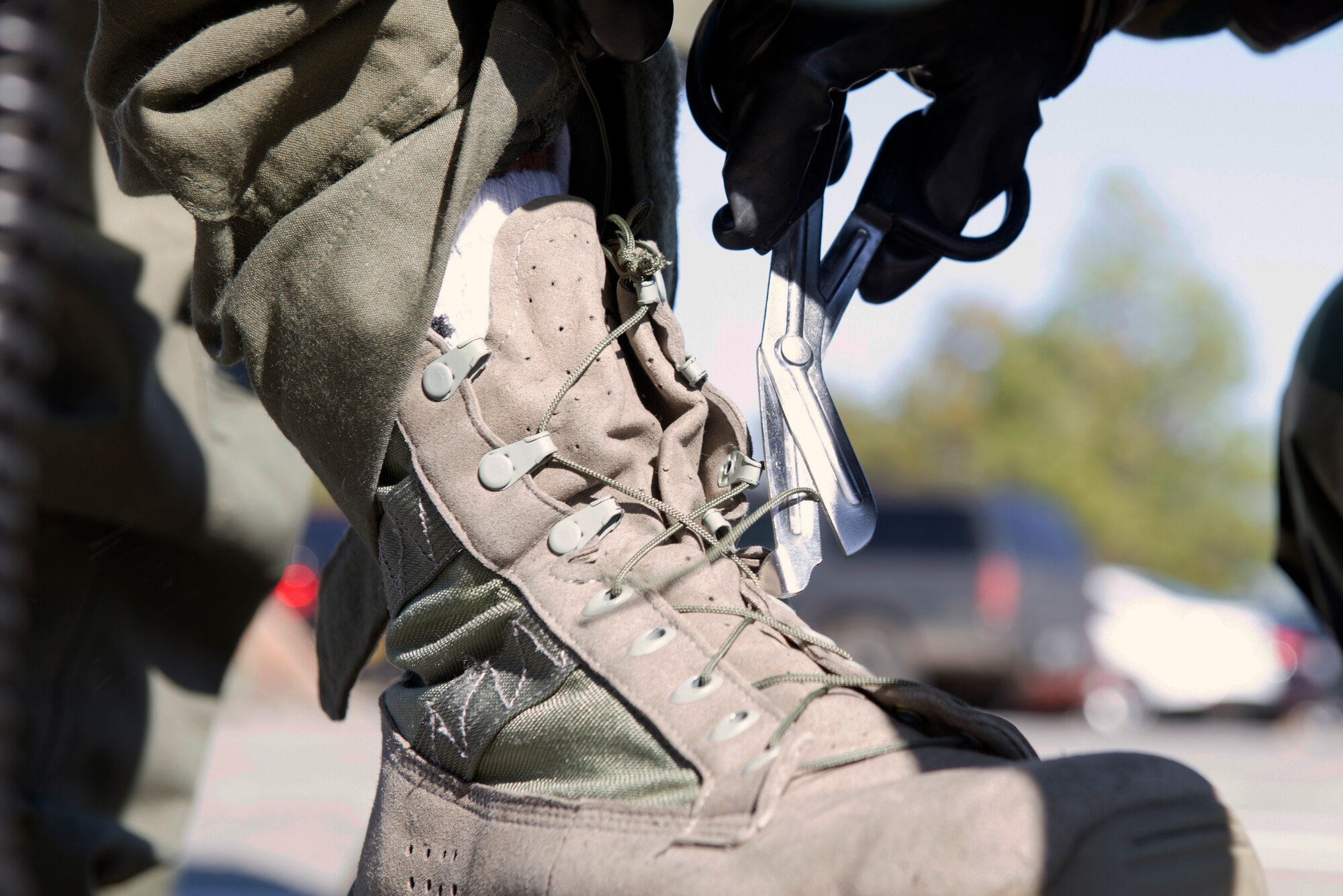 U.S. Air Force Airman 1st Class Jessica Jones, 23d Operations Support Squadron aircrew flight equipment technician, cuts a pilot’s boot laces during Aircrew Contamination Control Area training, Feb. 11, 2016, at Moody Air Force Base, Ga. AFE Airmen guide and explain the training line process  to ensure awareness of the safety measures implemented during training. (U.S. Air Force photo by Airman 1st Class Greg Nash/Released) 