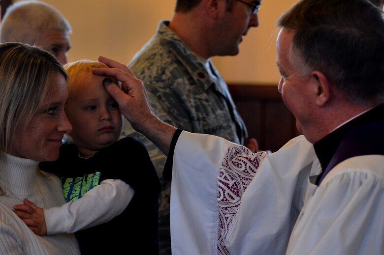 Monsignor Mark Rowan, 20th Fighter Wing catholic priest, puts ashes on the forehead of a child during an Ash Wednesday service at the Friendship Chapel at Shaw Air Force Base, S.C., Feb. 10, 2016. Ashes are applied to people’s foreheads to symbolize the dust from which God made humans. (U.S. Air Force photo by Senior Airman Michael Cossaboom) 