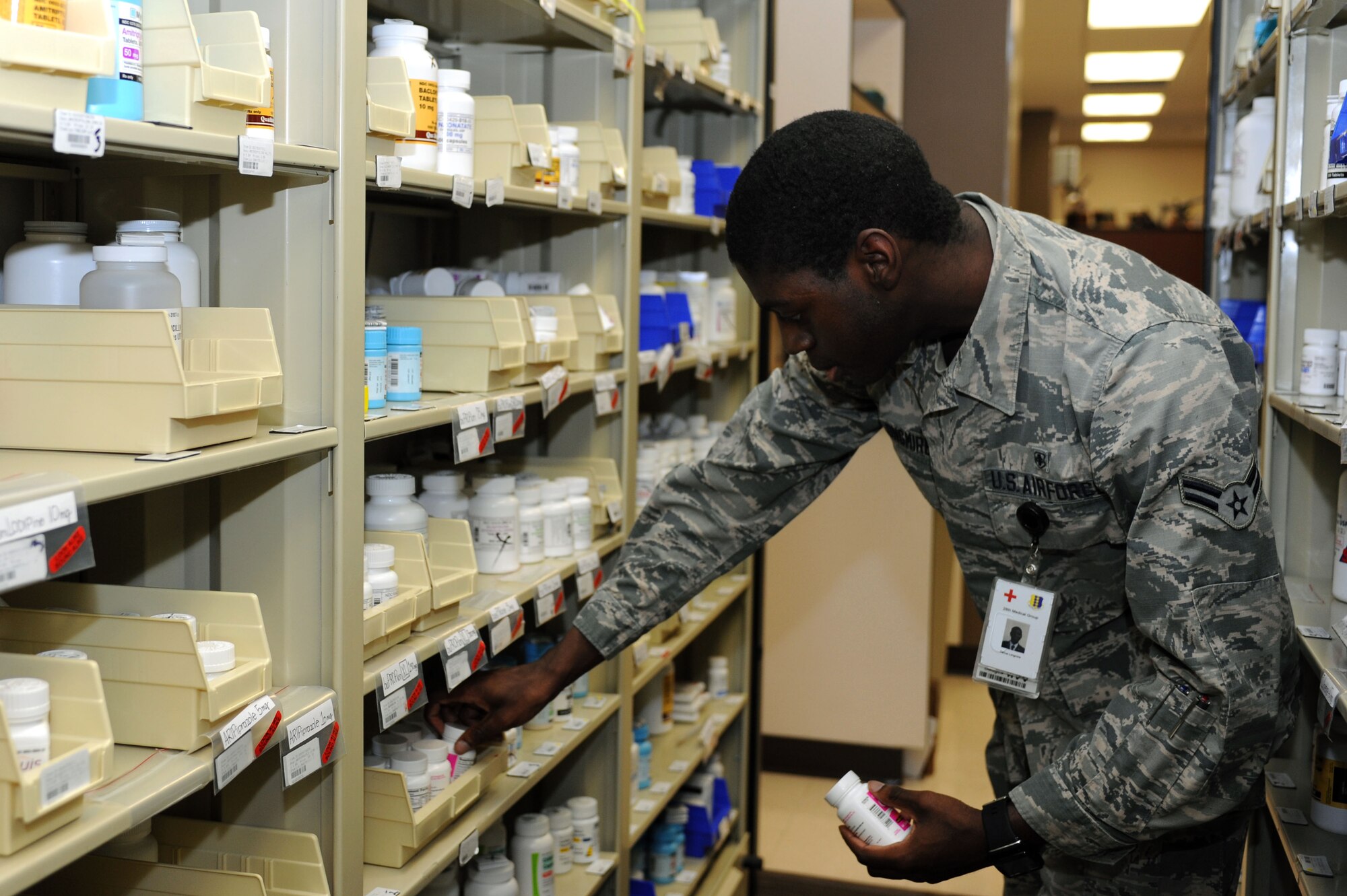 Airman 1st Class Darius Longmire, 28th Medical Support Squadron pharmacy technician, removes a bottle of Vitamin D from the pharmacy stock shelf at Ellsworth Air Force Base, S.D., Jan. 13, 2016. Pharmacy technicians remove medication to fill prescriptions for customers, and fill an average of 13,000 per month, including new scripts and refills. (U.S. Air Force photo by Senior Airman Hailey R. Staker/Released)