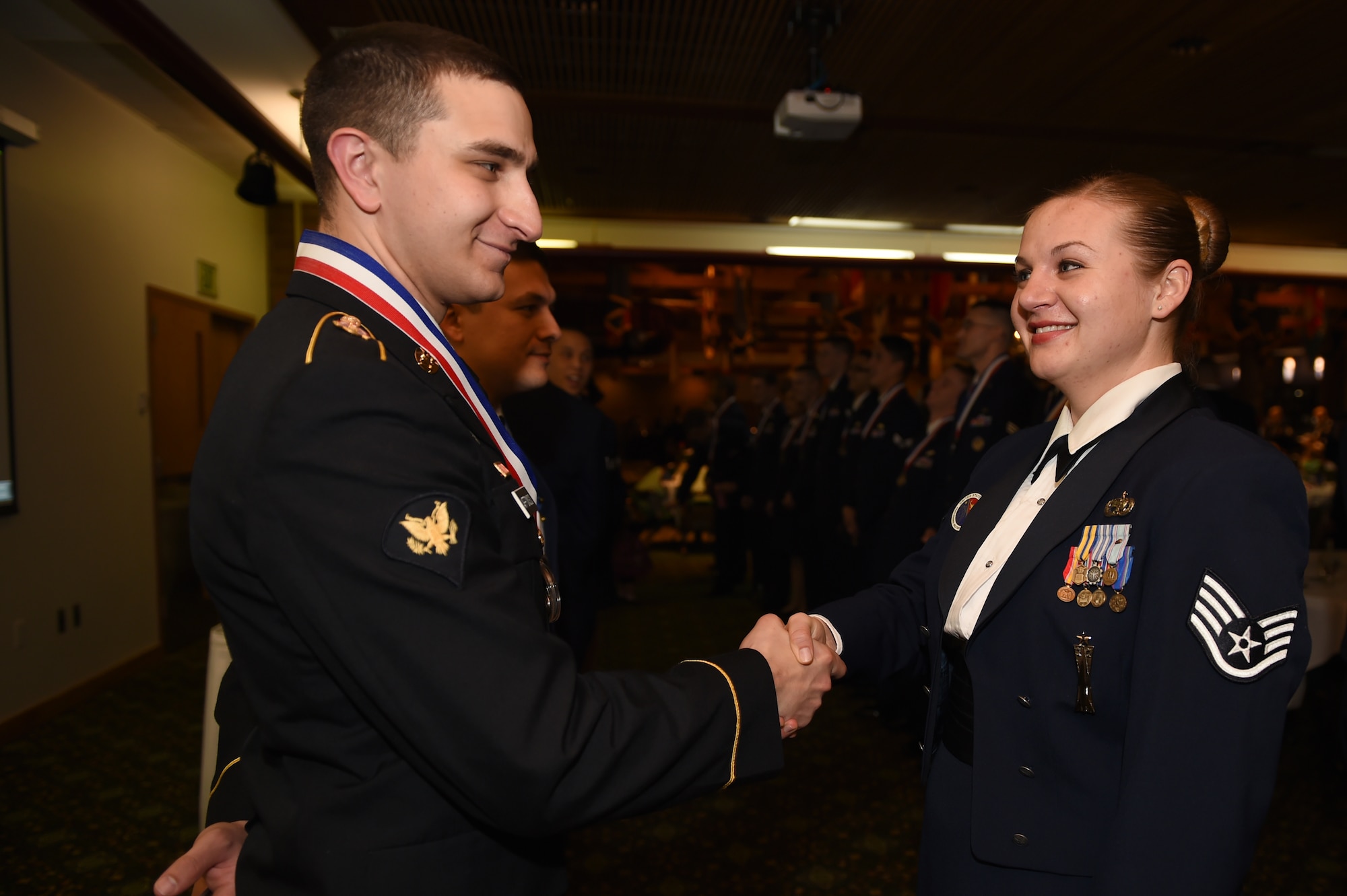 Spc. Andrew Affonso, Henry H. Lind NCO Academy information technology specialist, shakes the hand of his instructor, Staff Sgt. Jessica Raab, Joint Base Lewis-McChord Julius A. Kolb Airman Leadership School instructor, during the medallion ceremony at the Julius A. Kolb ALS graduation Feb. 10, 2016, at Joint Base Lewis-McChord, Wash. Affonso attend ALS right after graduating the Army’s Basic Leaders Course on Lewis. (U.S. Air Force photo/Staff Sgt. Naomi Shipley)