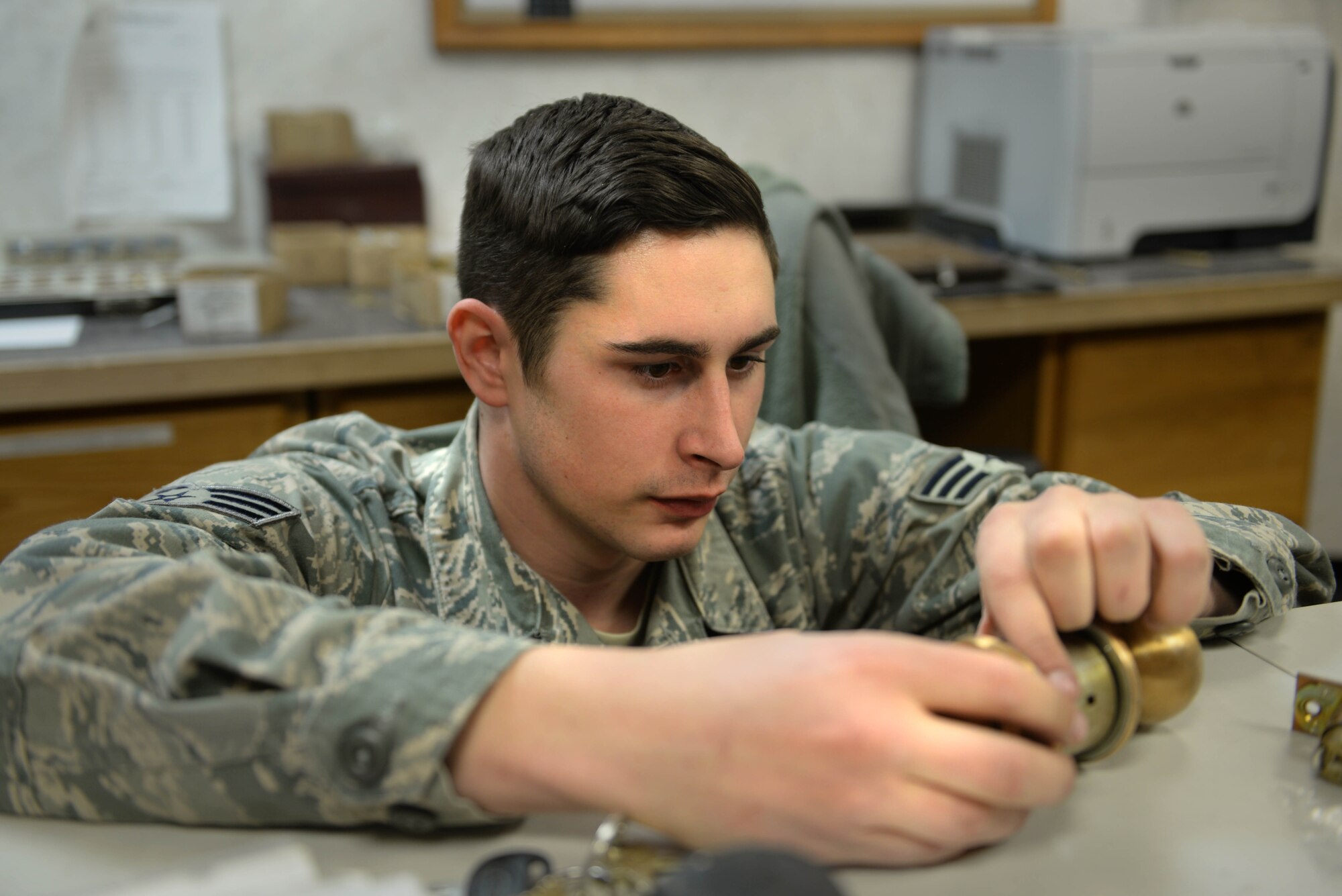 Senior Airman Ian Jerls, a structural journeyman assigned to the 5th Civil Engineer Squadron, assembles a door handle at Minot Air Force Base, N.D., Feb. 11, 2016. The 5th CES lock shop creates lock cores and keys to ensure building security throughout Minot AFB. (U.S. Air Force photo/ Airman 1st Class Jessica Weissman)