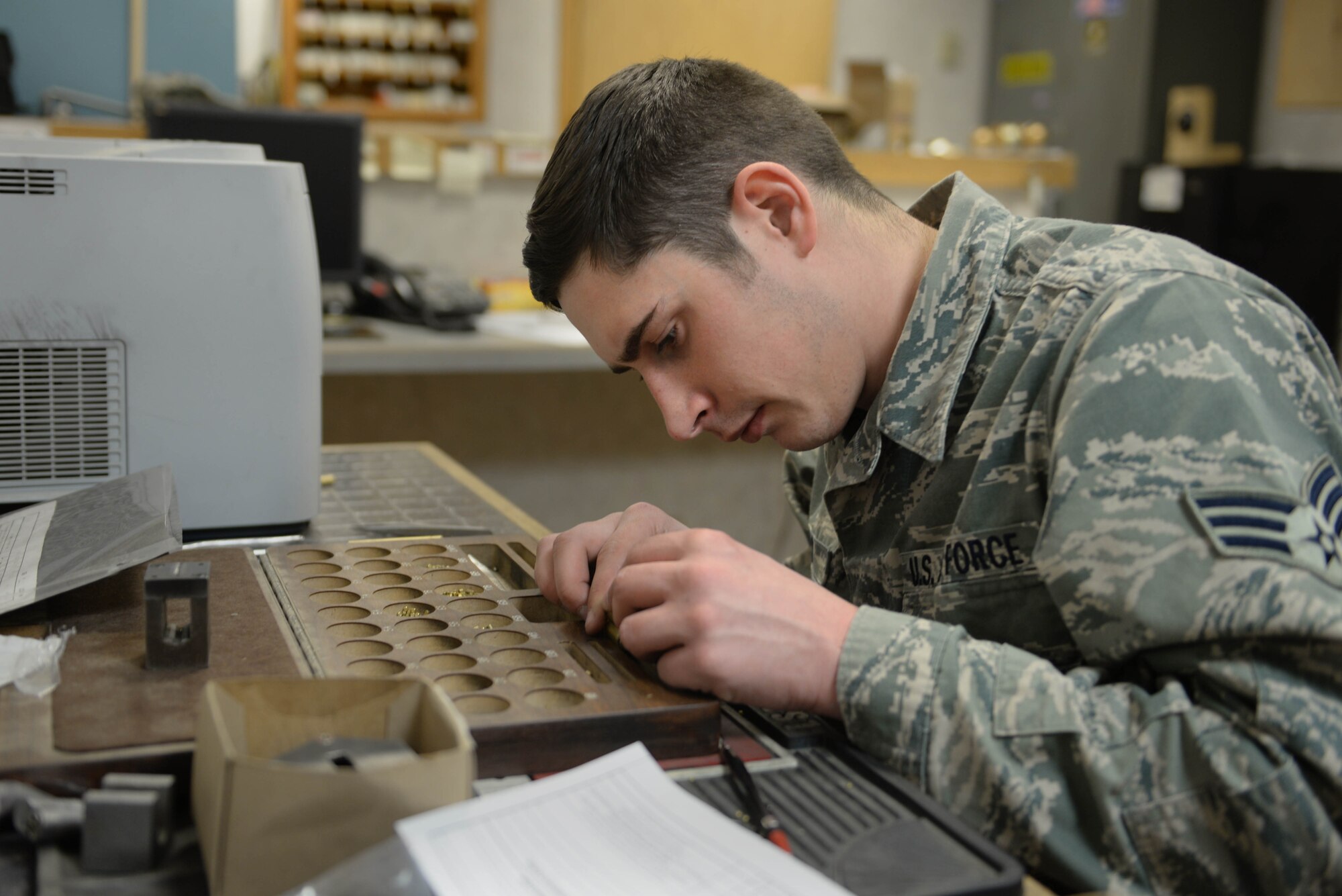 Senior Airman Ian Jerls, a structural journeyman assigned to the 5th Civil Engineer Squadron, carefully places pins into a lock core at Minot Air Force Base, N.D., Feb. 11, 2016. Pins are precisely sized to create a unique core to match a specific key. (U.S. Air Force photo/ Airman 1st Class Jessica Weissman)