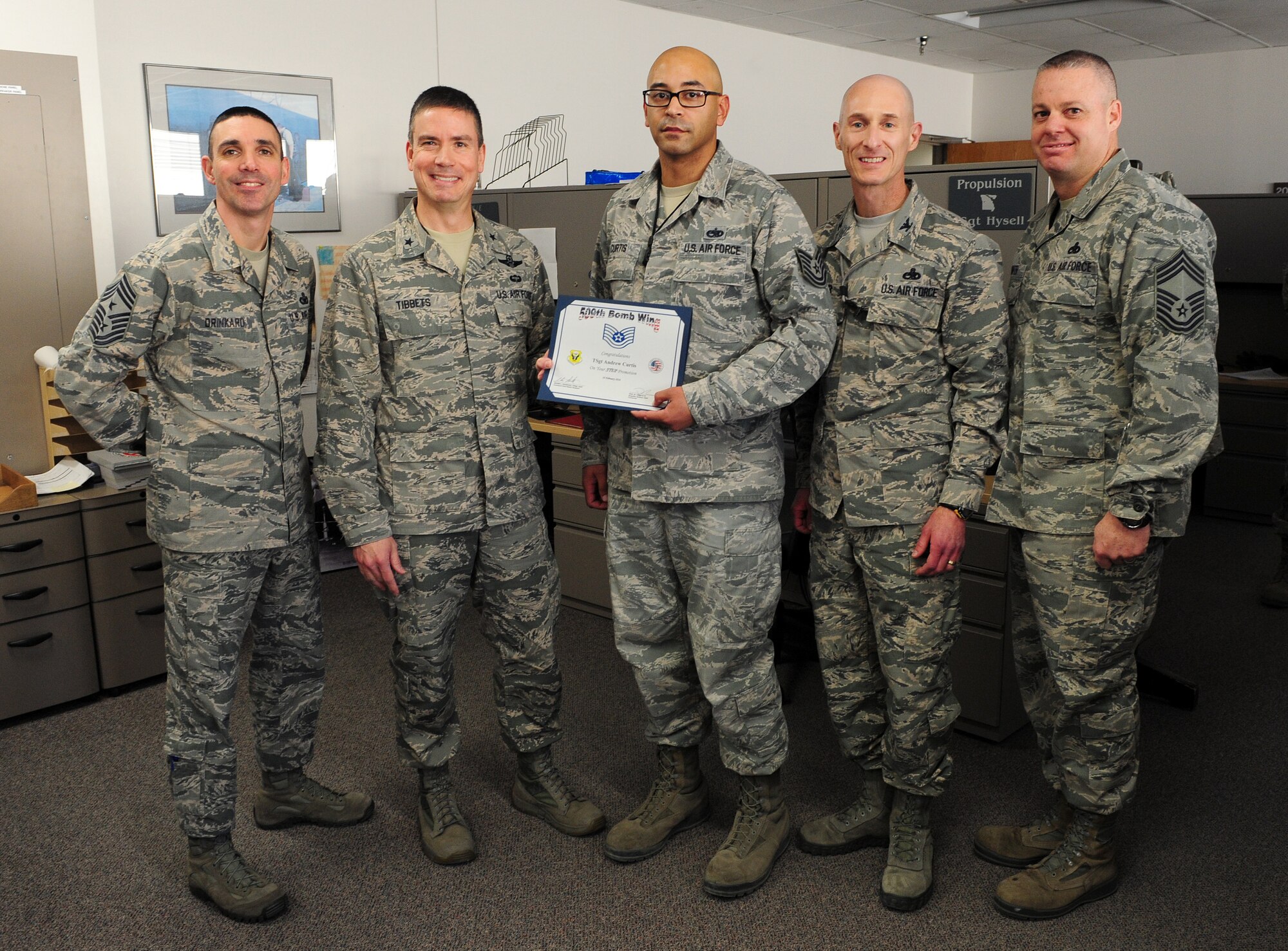 U.S. Air Force Tech. Sgt. Andrew Curtis, center, a quality assurance inspector assigned to the 509th Maintenance Group, stands with Brig. Gen. Paul Tibbets IV, the 509th Bomb Wing commander, and senior leadership after being notified of his immediate promotion to technical sergeant at Whiteman Air Force Base, Mo., Feb. 11, 2016. Through the Stripes for Exceptional Performance (STEP) program, Curtis competed at the MAJCOM level and was one of eight selected to be promoted from the rank of staff sergeant to technical sergeant. (U.S. Air Force photo by Airman 1st Class Jazmin Smith)