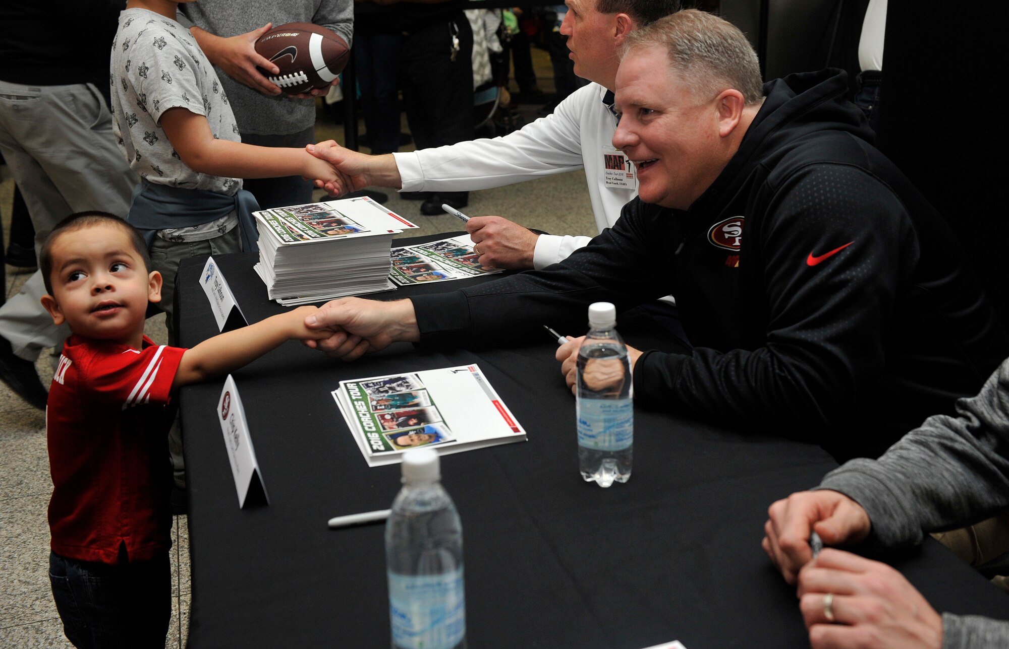 Chip Kelly, San Francisco 49ers head coach, shakes hands with a young fan during a meet-and-greet for the 2016 Coaches Tour Feb. 14, 2016, at Ramstein Air Base, Germany. Fans had the opportunity to meet, talk with and get autographs from four coaches from both collegiate and professional leagues. (U.S. Air Force photo/Airman 1st Class Larissa Greatwood)