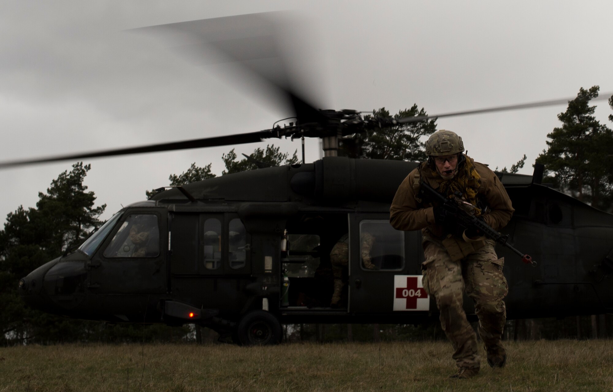 Senior Airman Tormod Lillekroken, 2nd Air Support Operations Squadron tactical air control party member, rejoins his team after helping a simulated casualty onto a UH-60 for medical evacuation during training at U.S. Army Garrison Bavaria in Vilseck, Germany, Feb. 8, 2016. The training consisted of calling in close air support, neutralizing opposing forces and practicing medical evacuation by helicopter. (U.S. Air Force photo/Senior Airman Jonathan Stefanko)